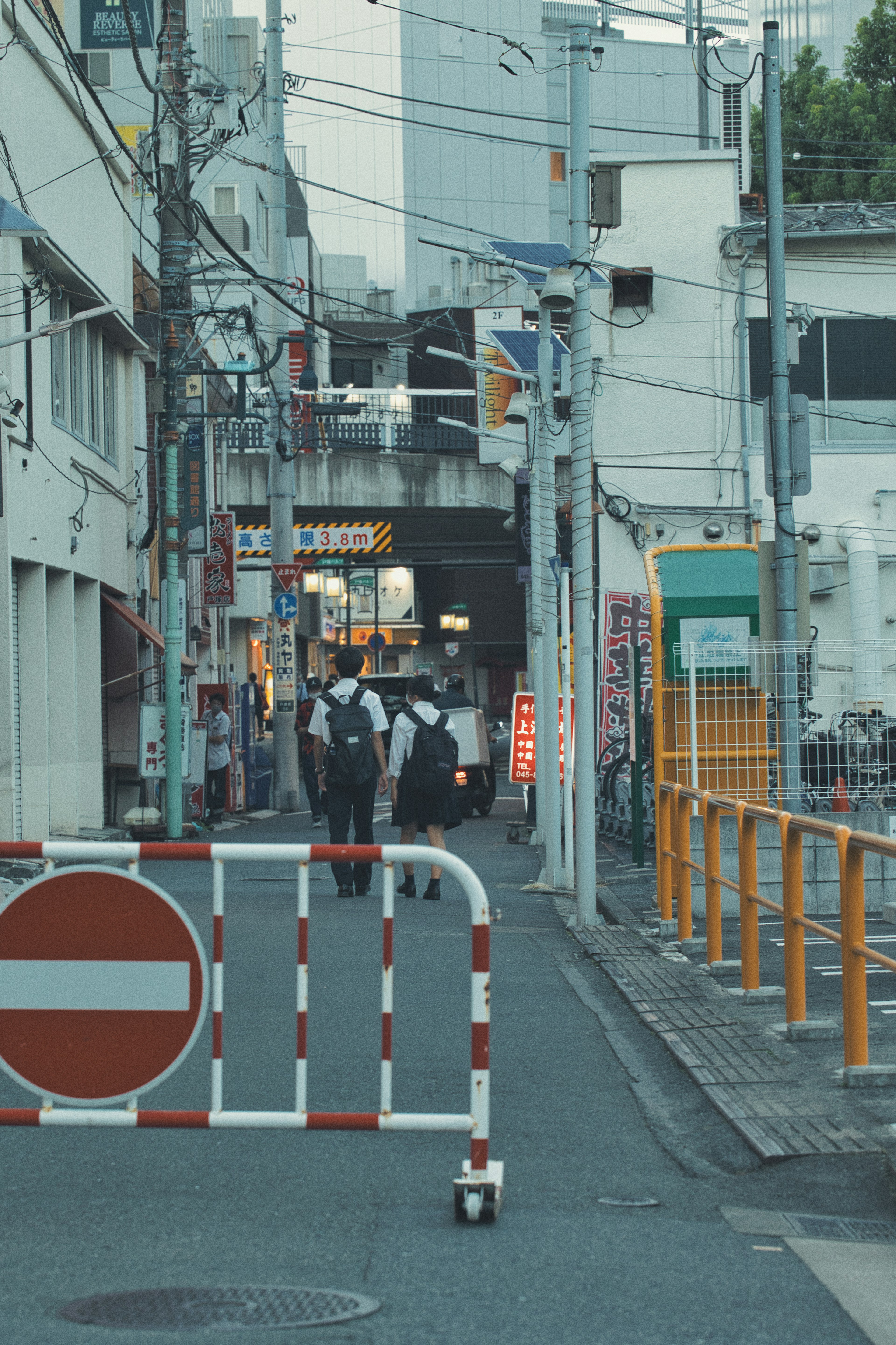 狭い通りに立ち止まっている数人の人々と交通規制のバリアがある風景