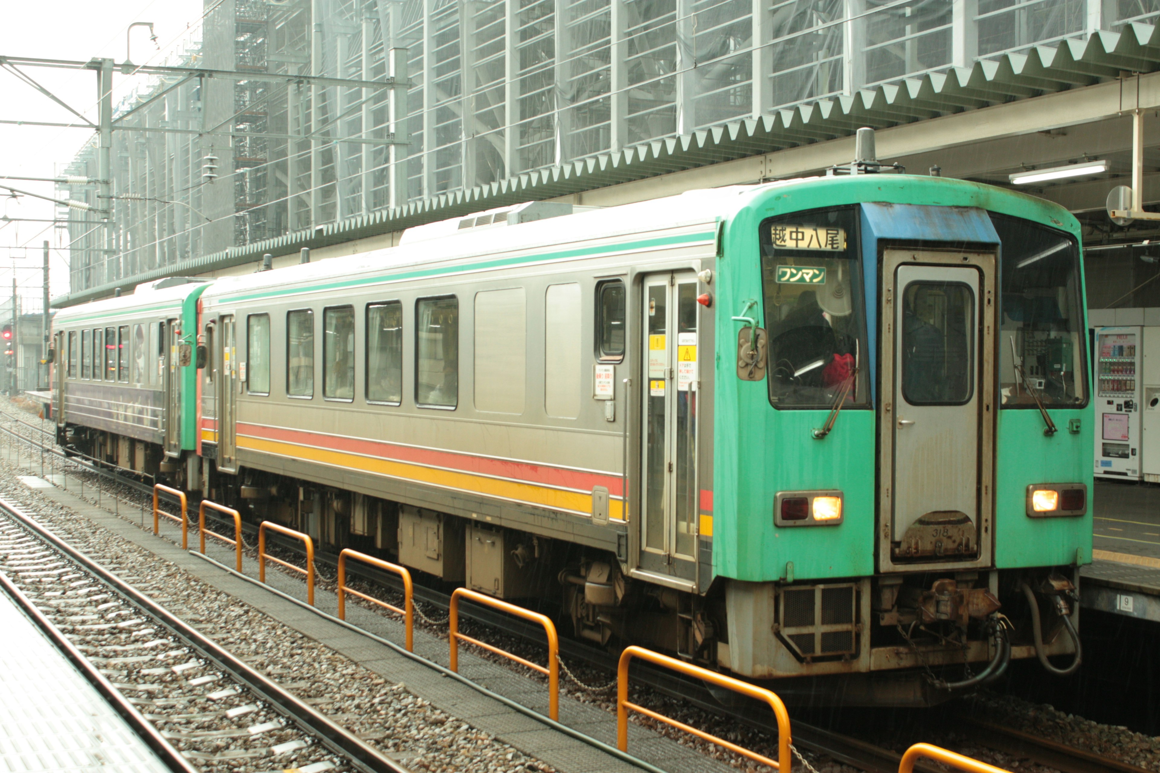 Tren verde y plateado estacionado en una estación