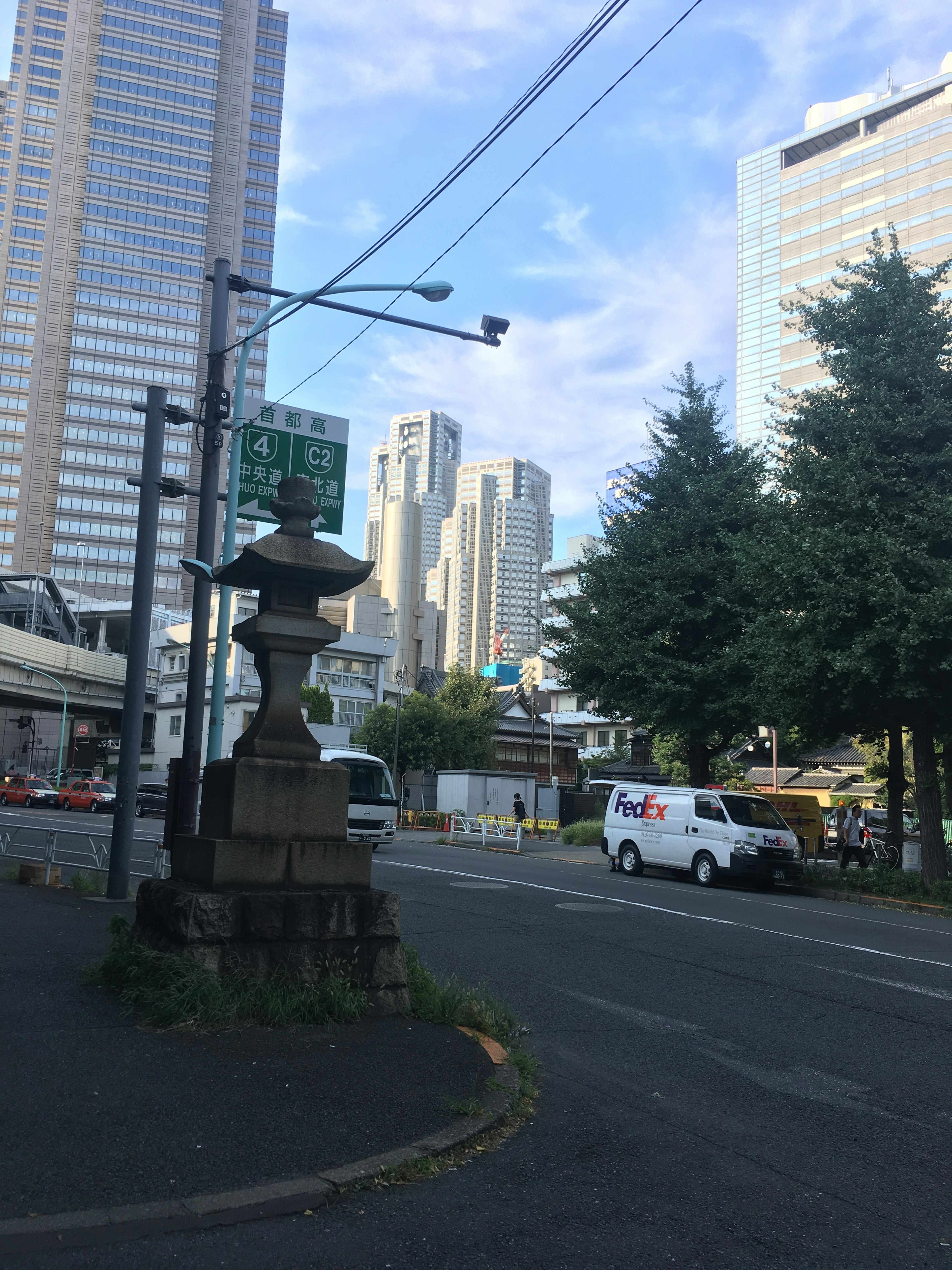 高層ビルと街路樹のある交差点に立つ灯籠