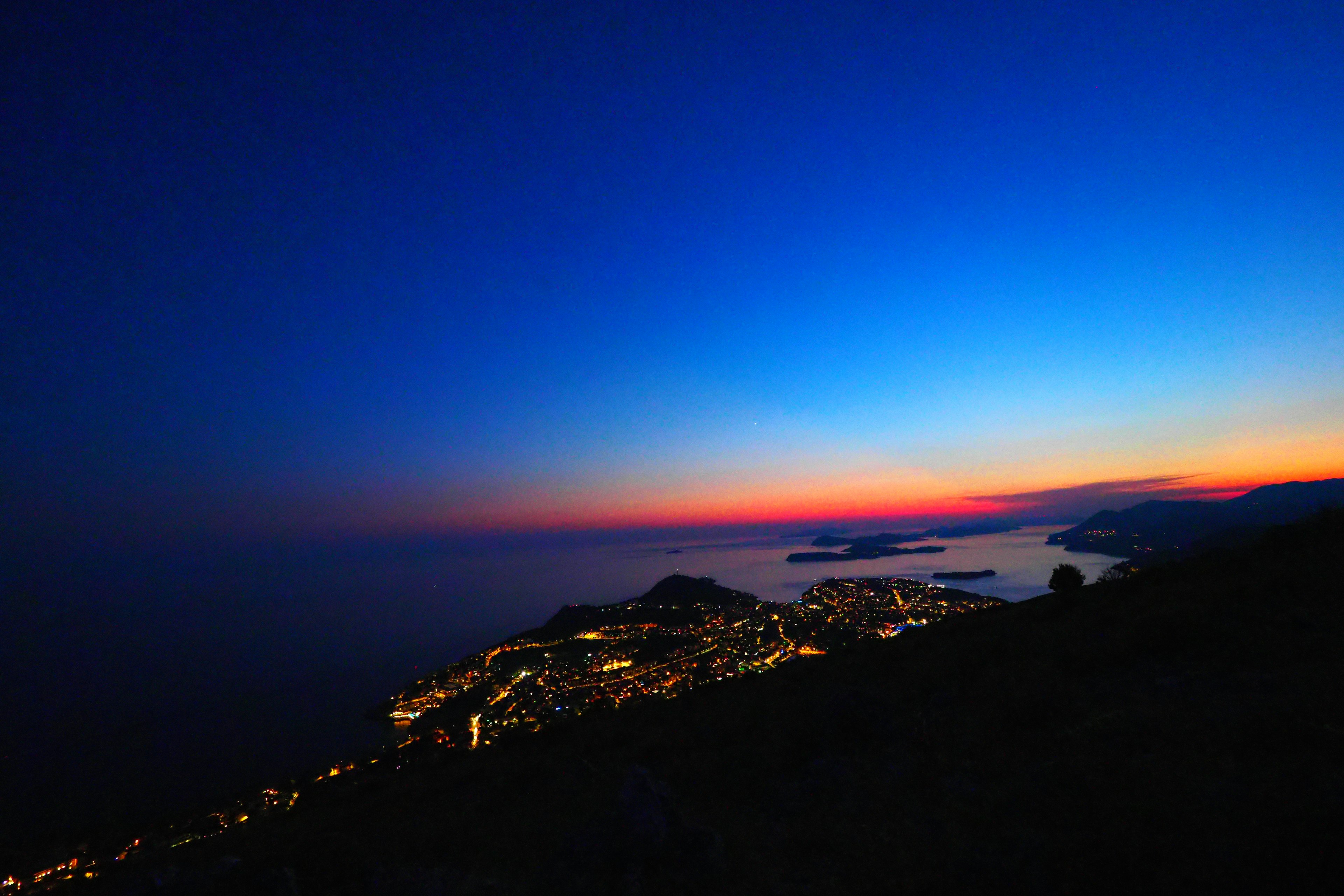 Stupendo tramonto costiero con luci della città che brillano