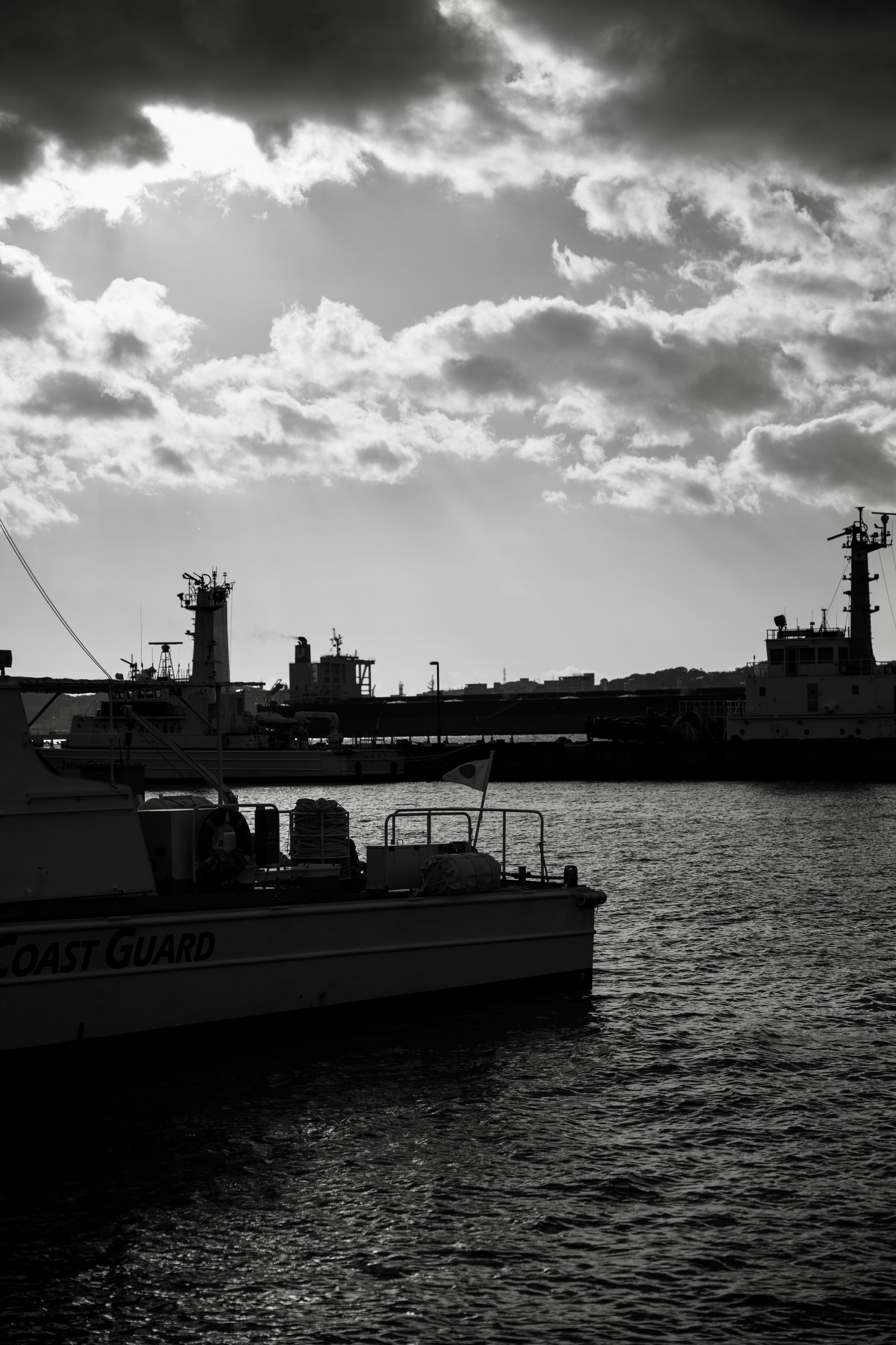 Black and white seascape featuring boats and clouds reflected on the water