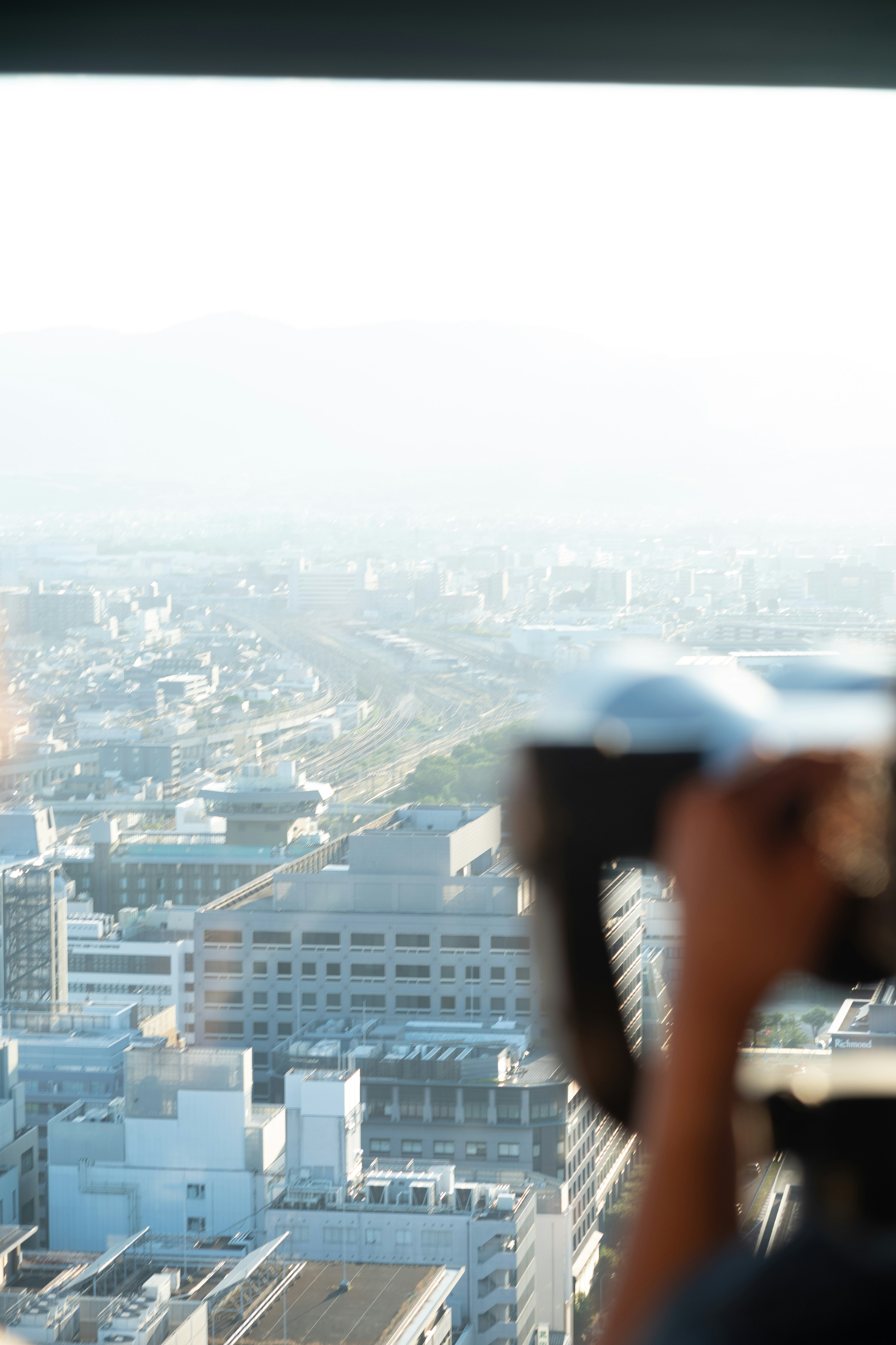 A hand holding a camera capturing a cityscape