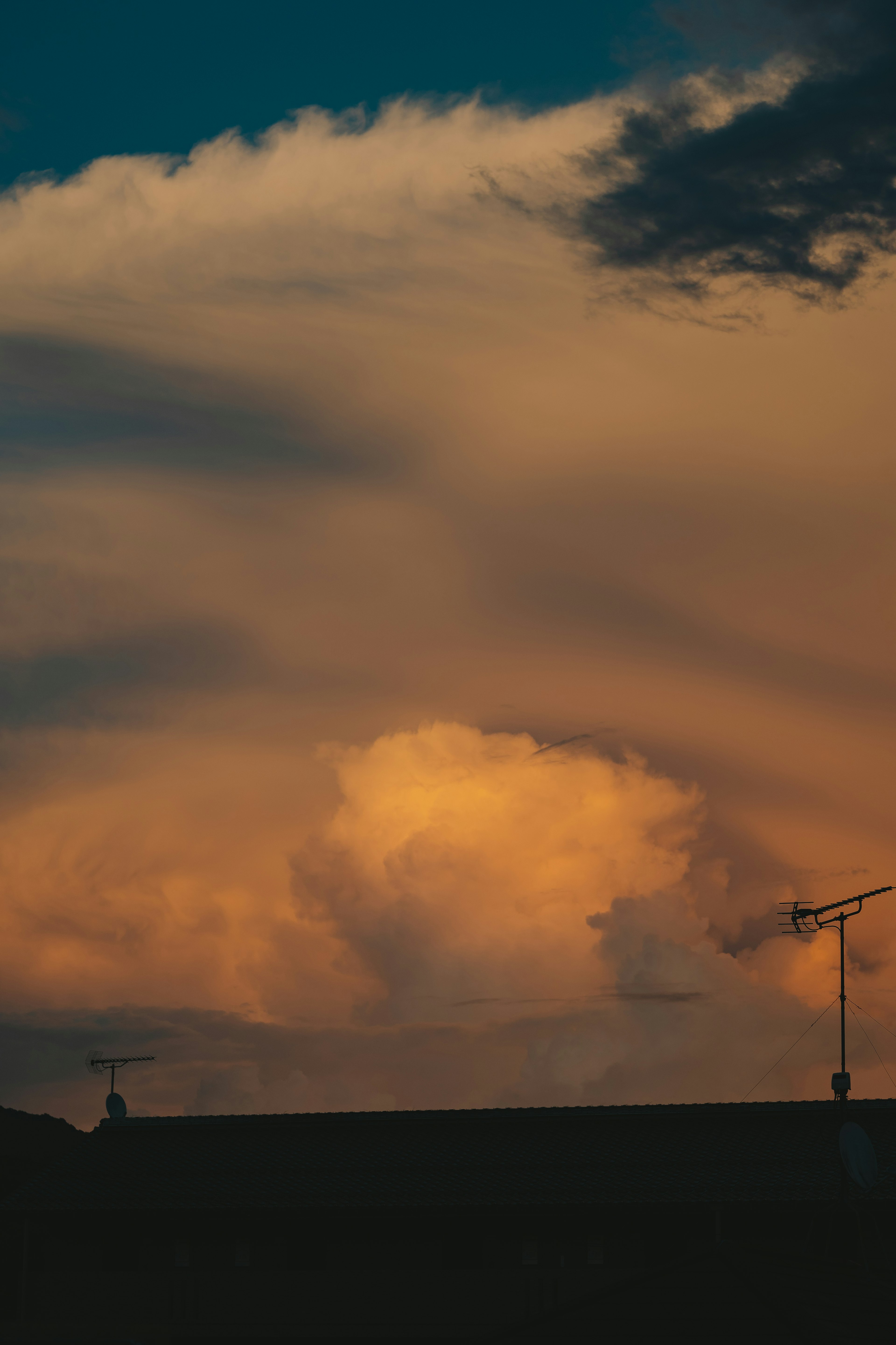 Silhouette of rooftops against a sunset sky with vibrant clouds