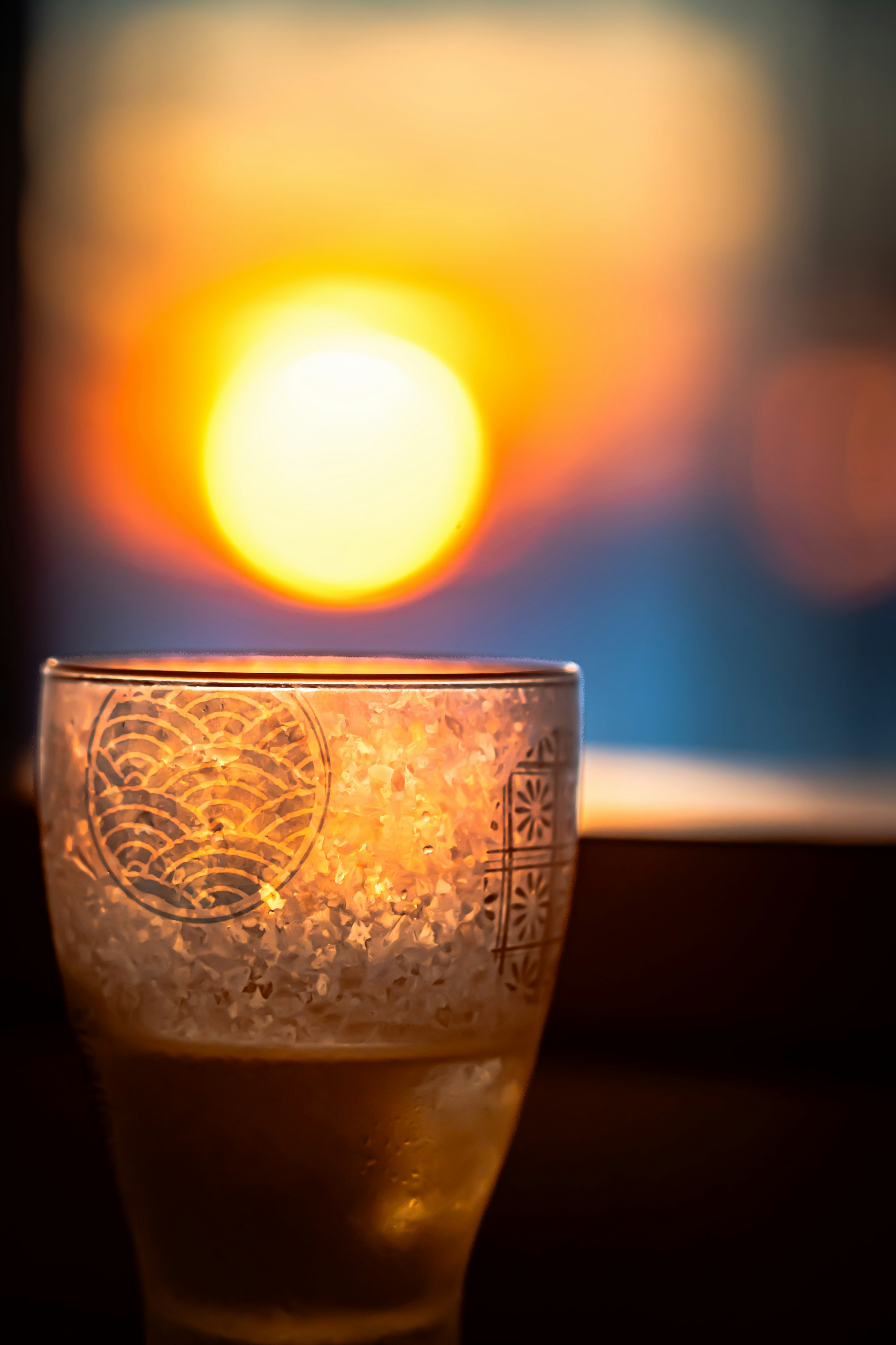 Close-up of a glass with sunset in the background