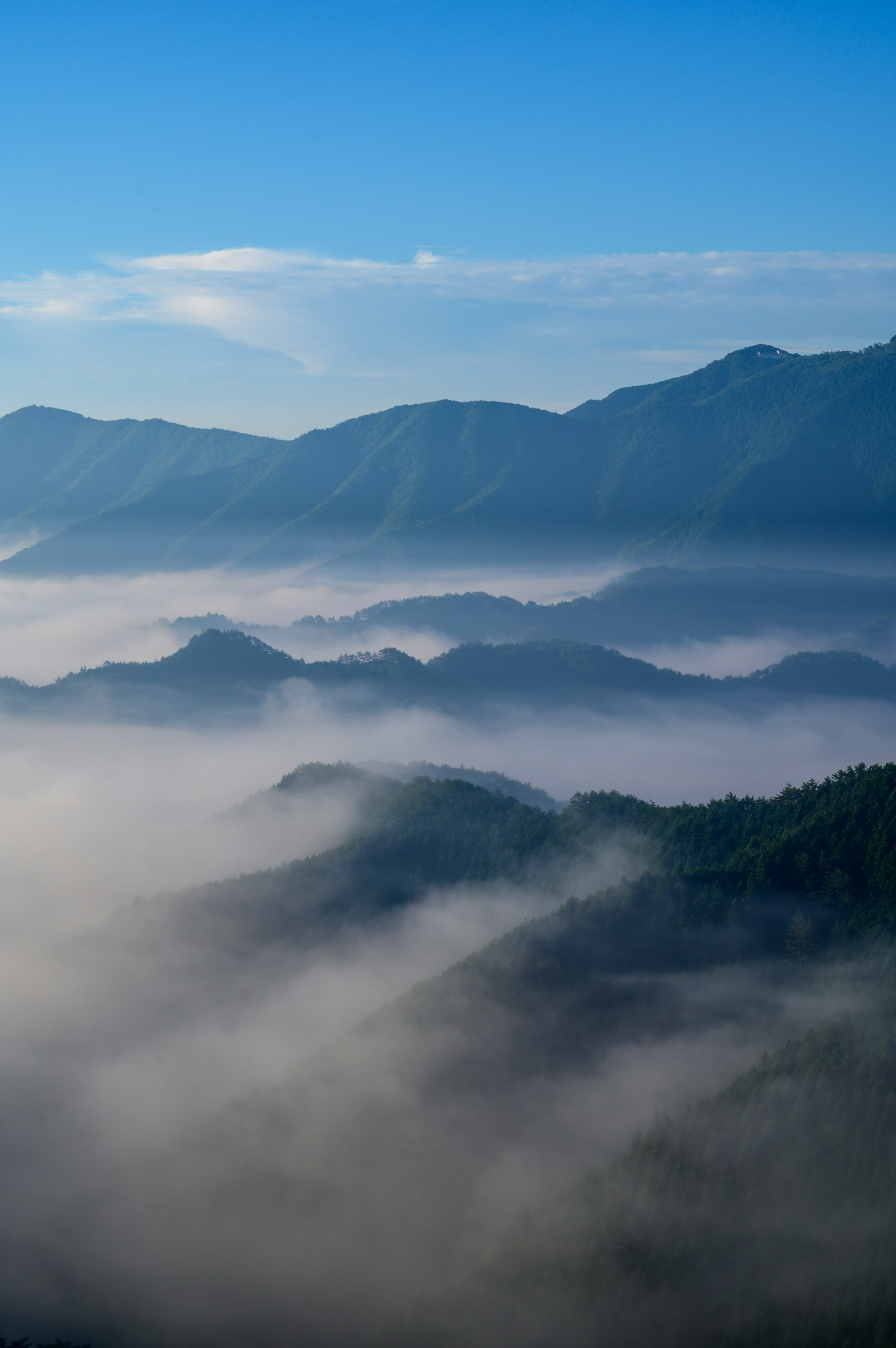 Paesaggio di montagne coperte di nebbia con cielo blu