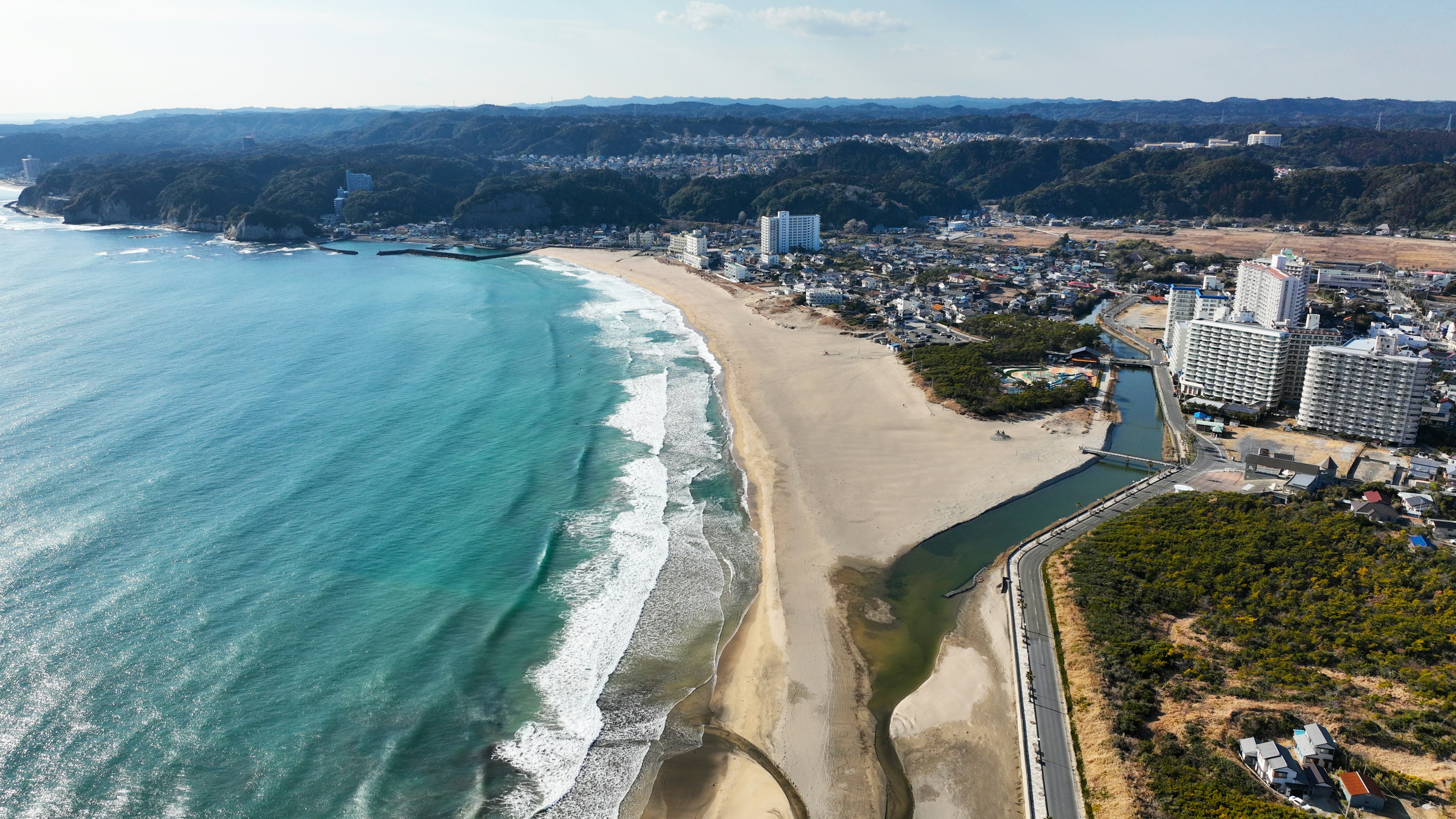 Pemandangan udara garis pantai dengan laut biru dan pantai berpasir, bangunan resor