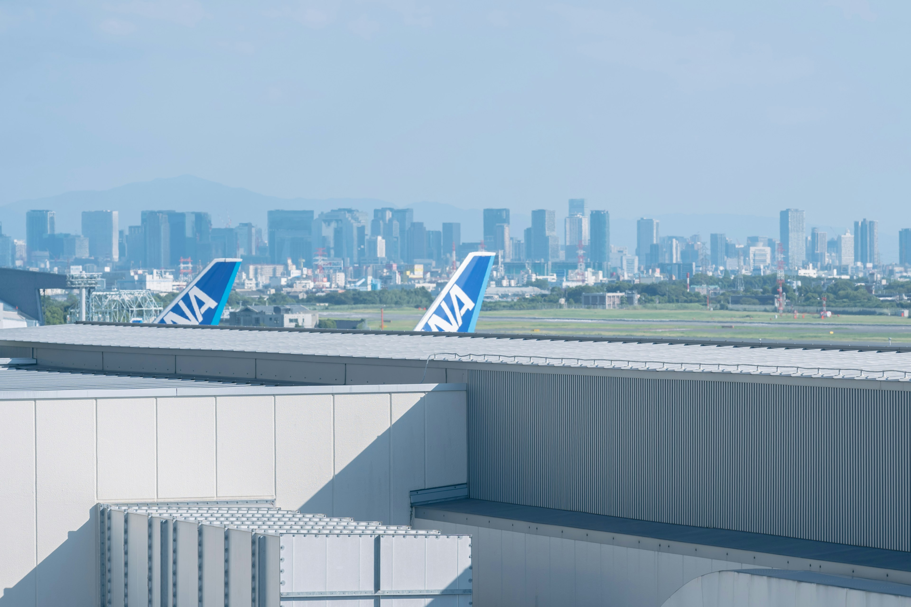 Colas de aviones en un aeropuerto con horizonte urbano de fondo