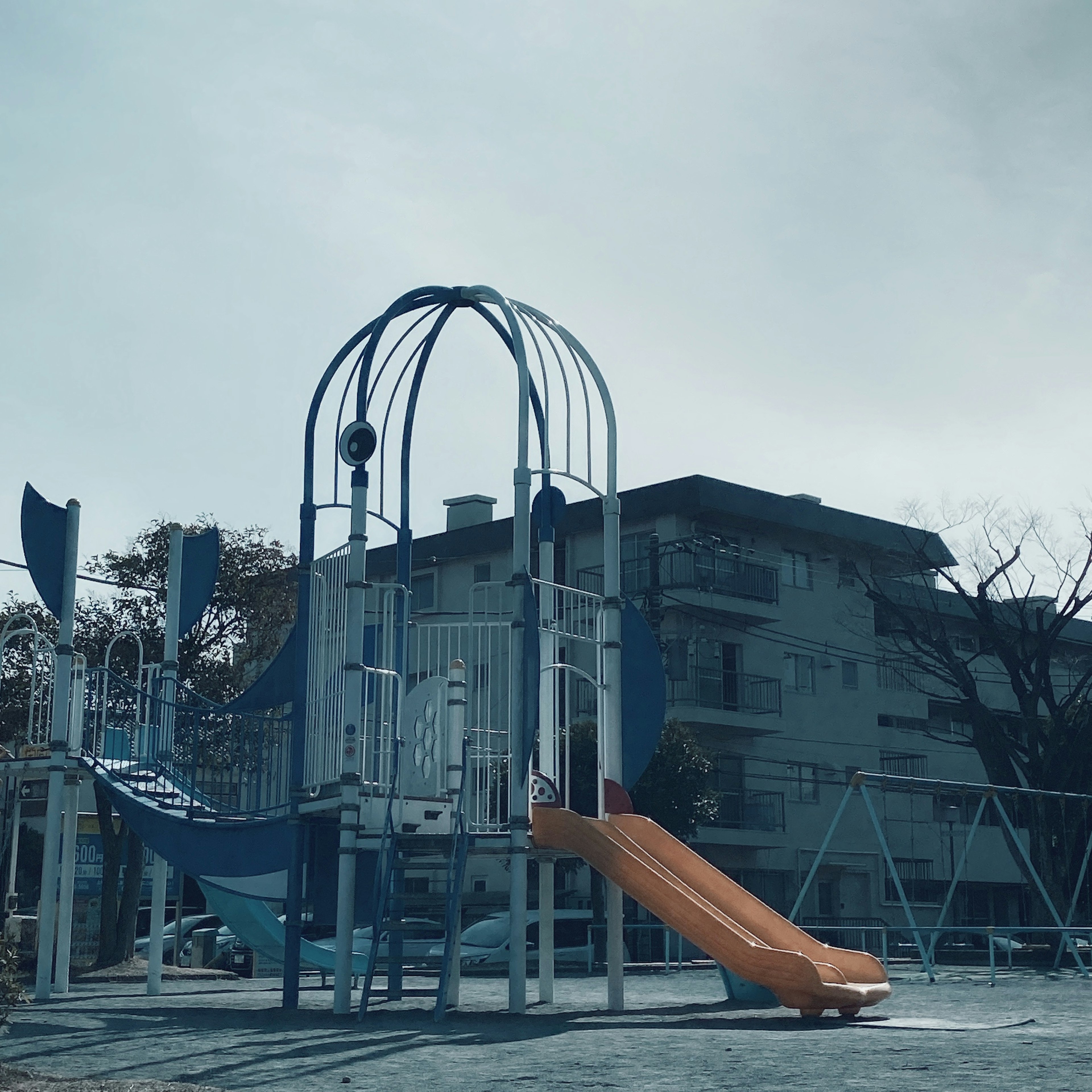 Playground with slide and play equipment building in the background