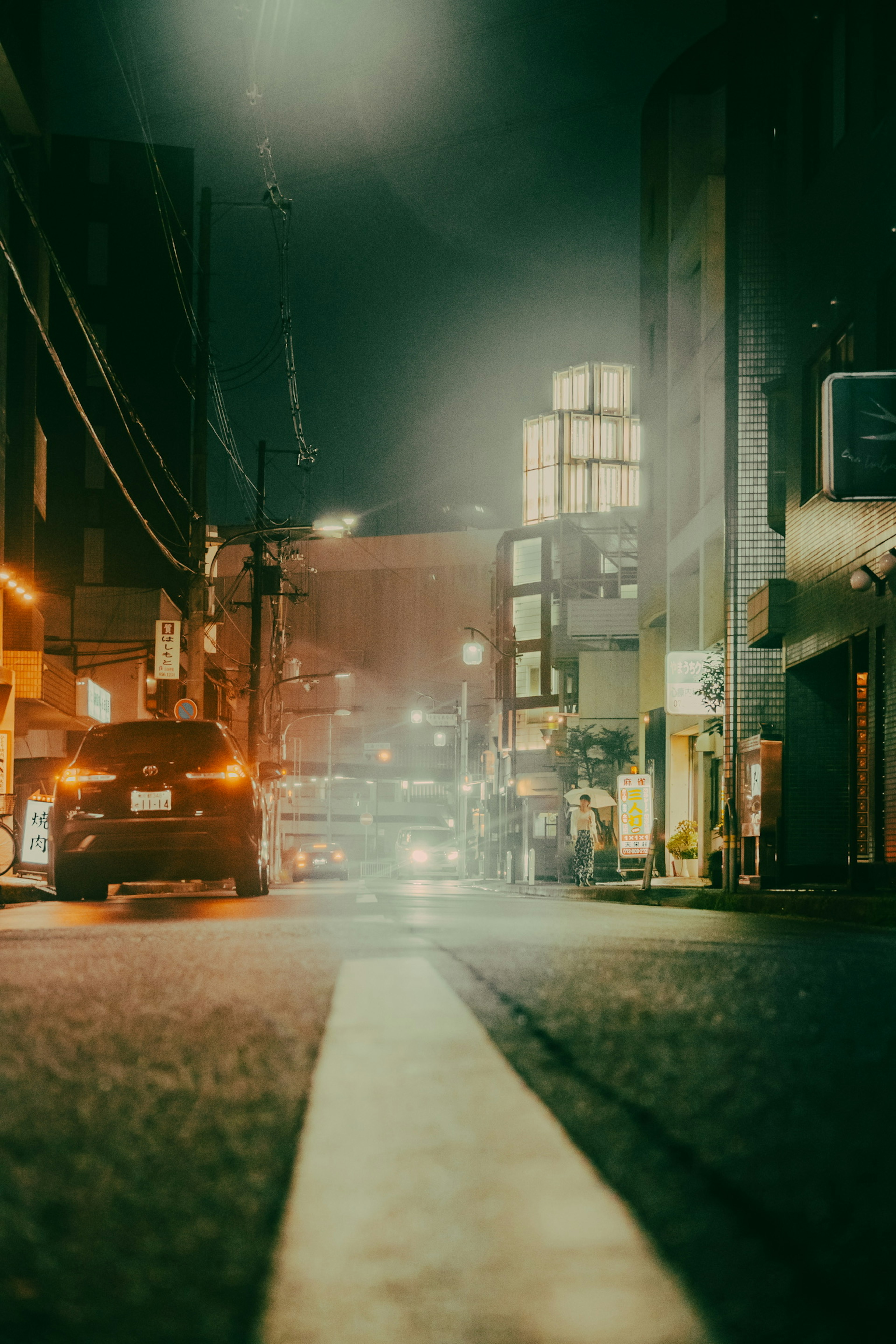 Street view at night with illuminated buildings and fog