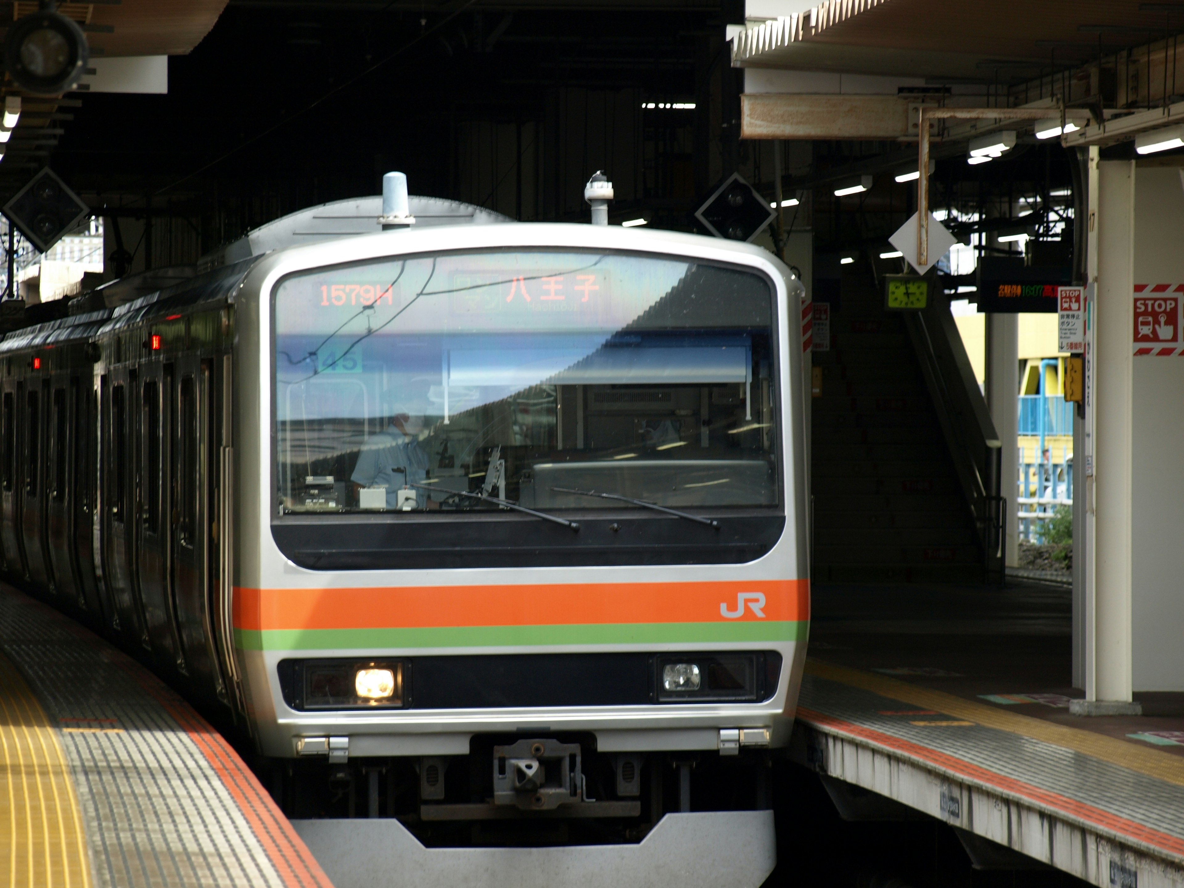 緑とオレンジのストライプが特徴のJRの電車が駅に到着する様子