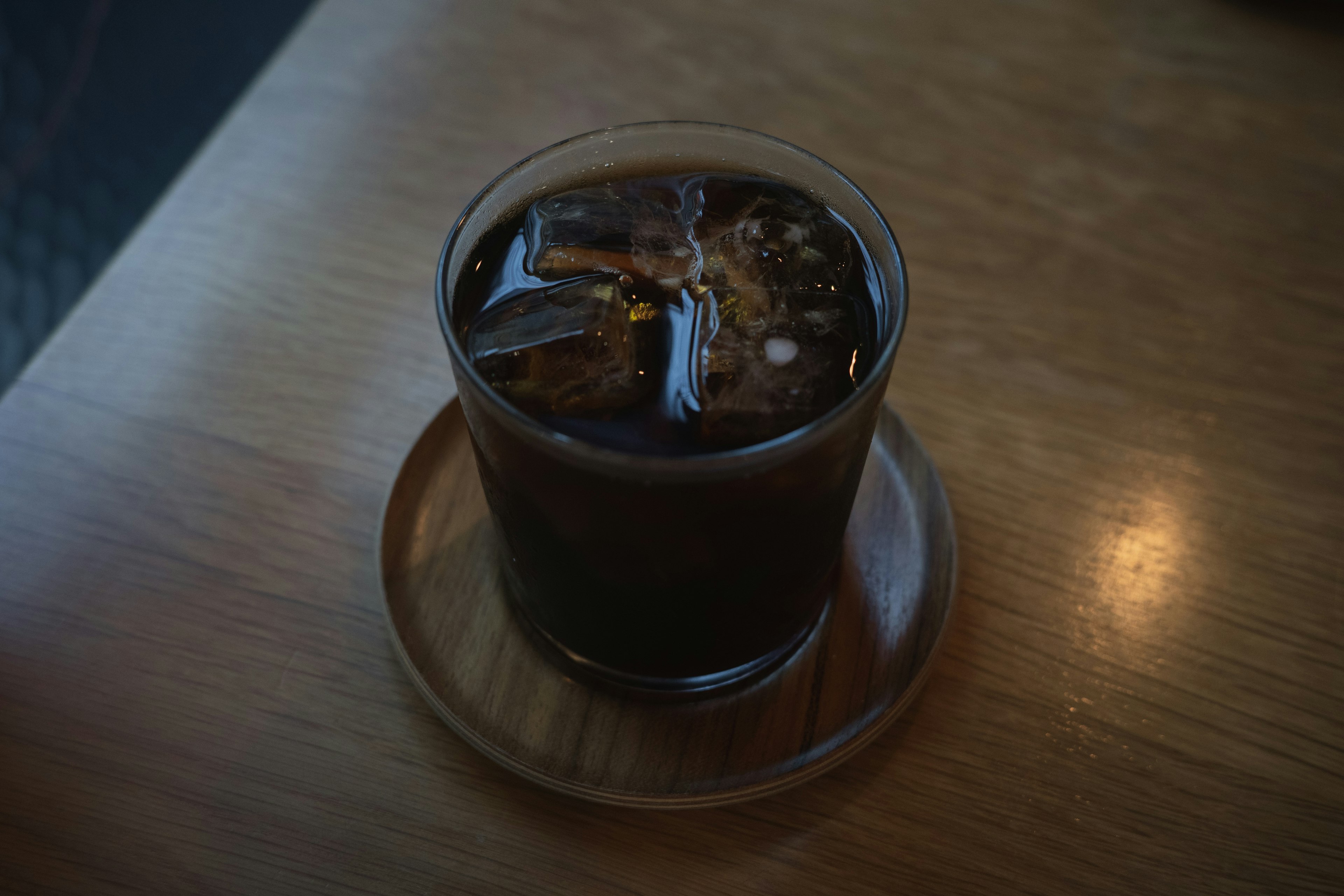 Glass of iced coffee on a wooden coaster