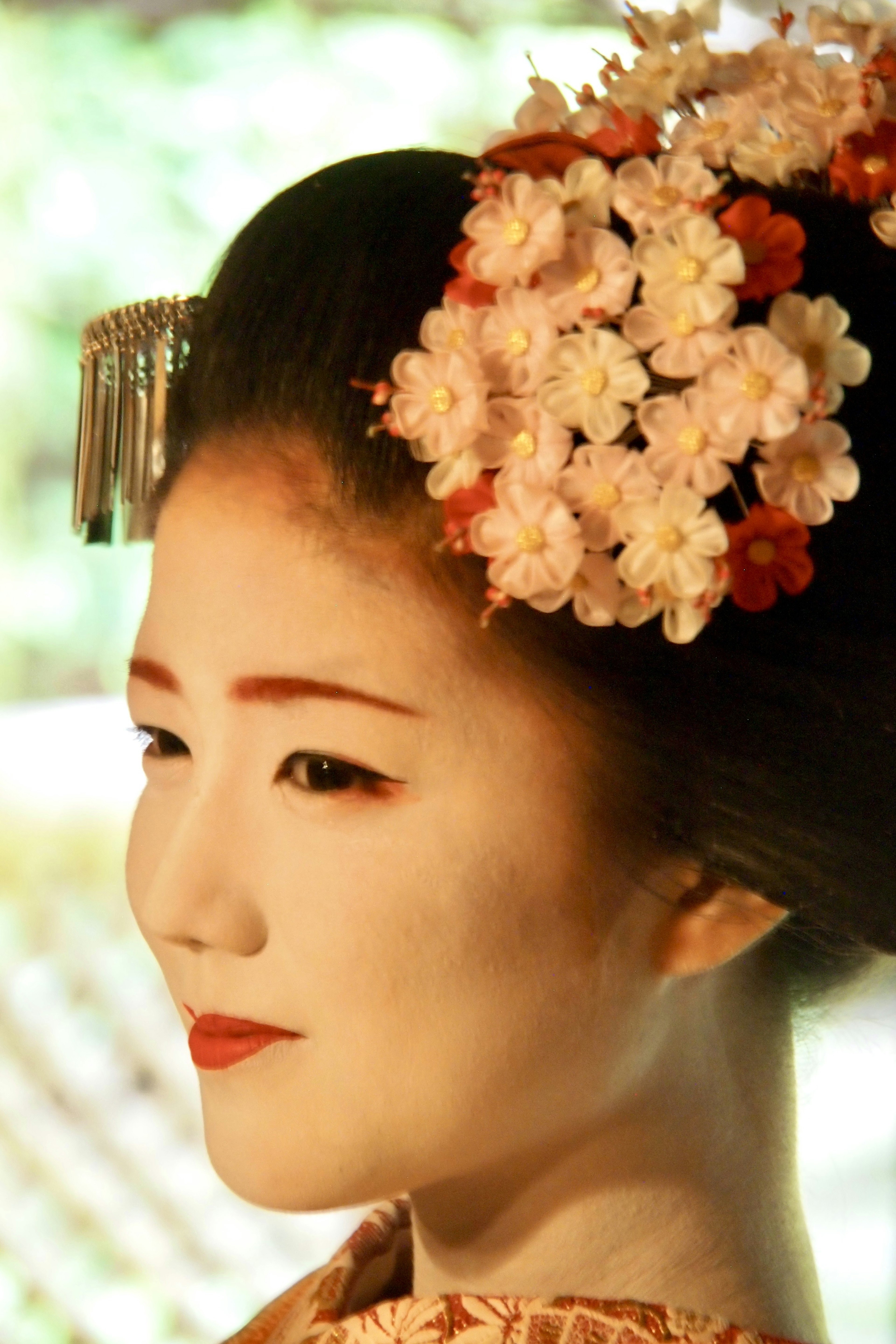 Perfil de una mujer en un hermoso kimono con adornos florales en el cabello y maquillaje tradicional