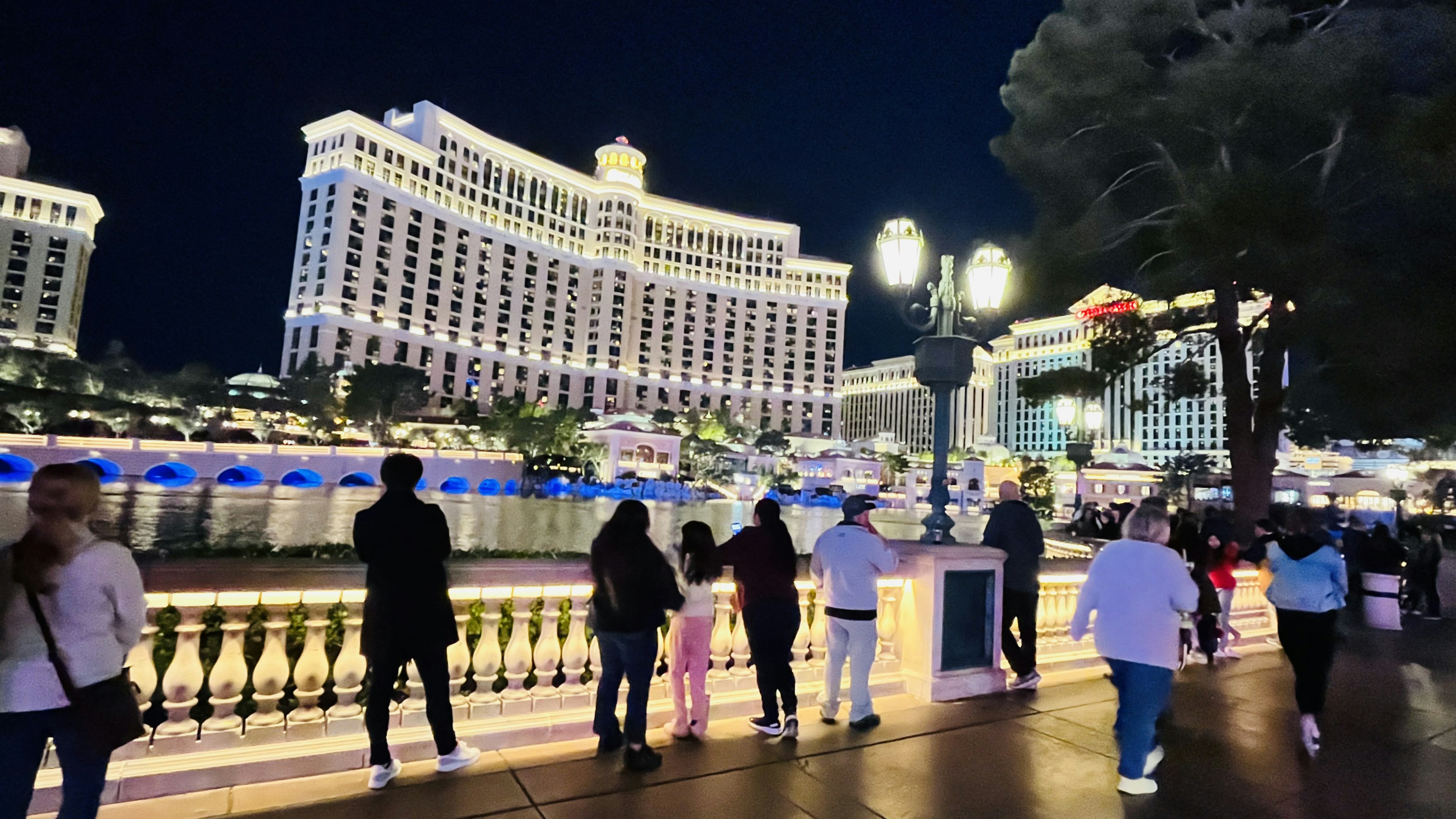 Menschen, die die schöne Aussicht auf das Bellagio Hotel und die Fontänen-Show in Las Vegas bei Nacht beobachten