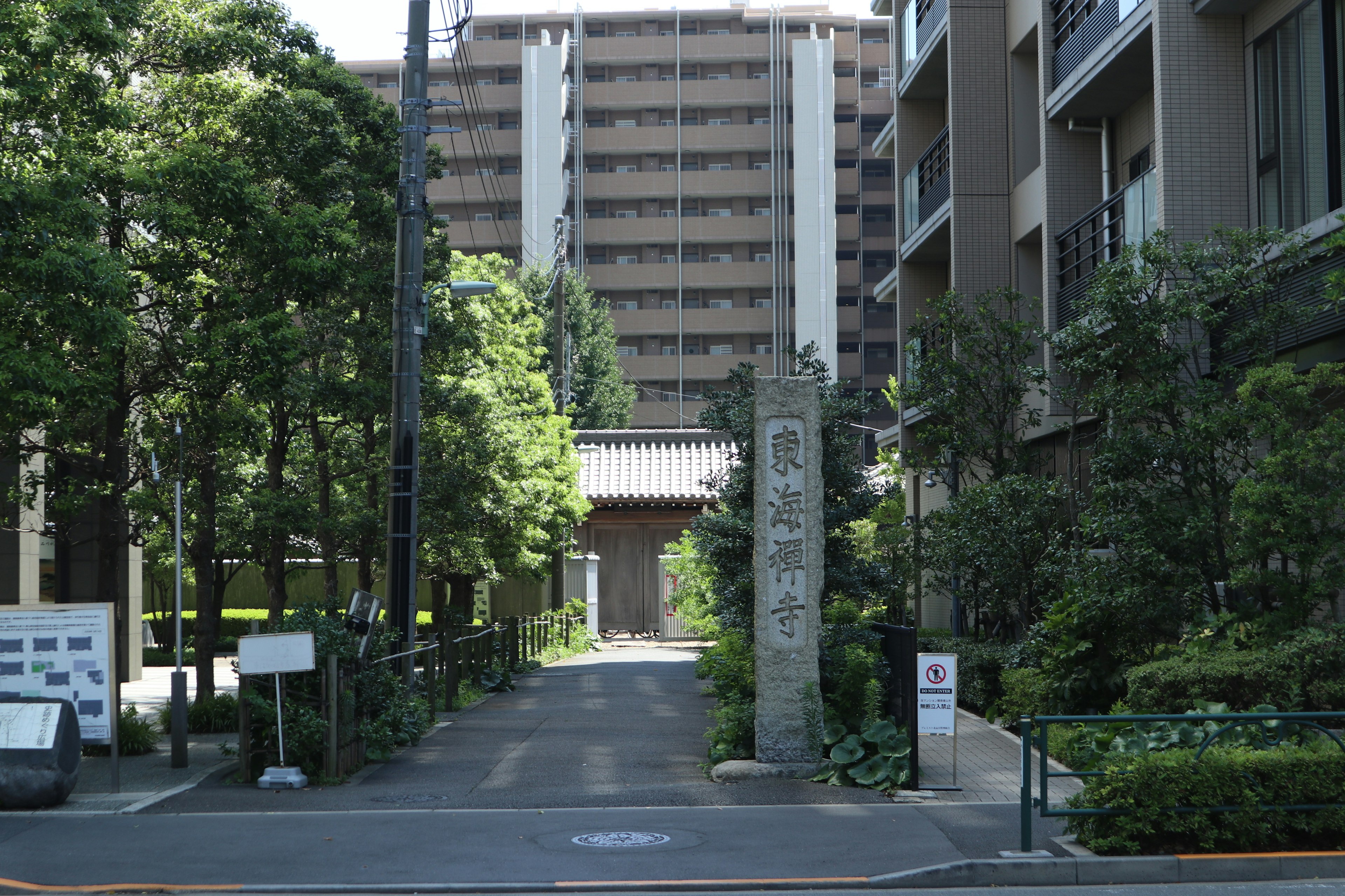 Entrée d'une rue avec une vieille porte en pierre entourée de verdure et un immeuble