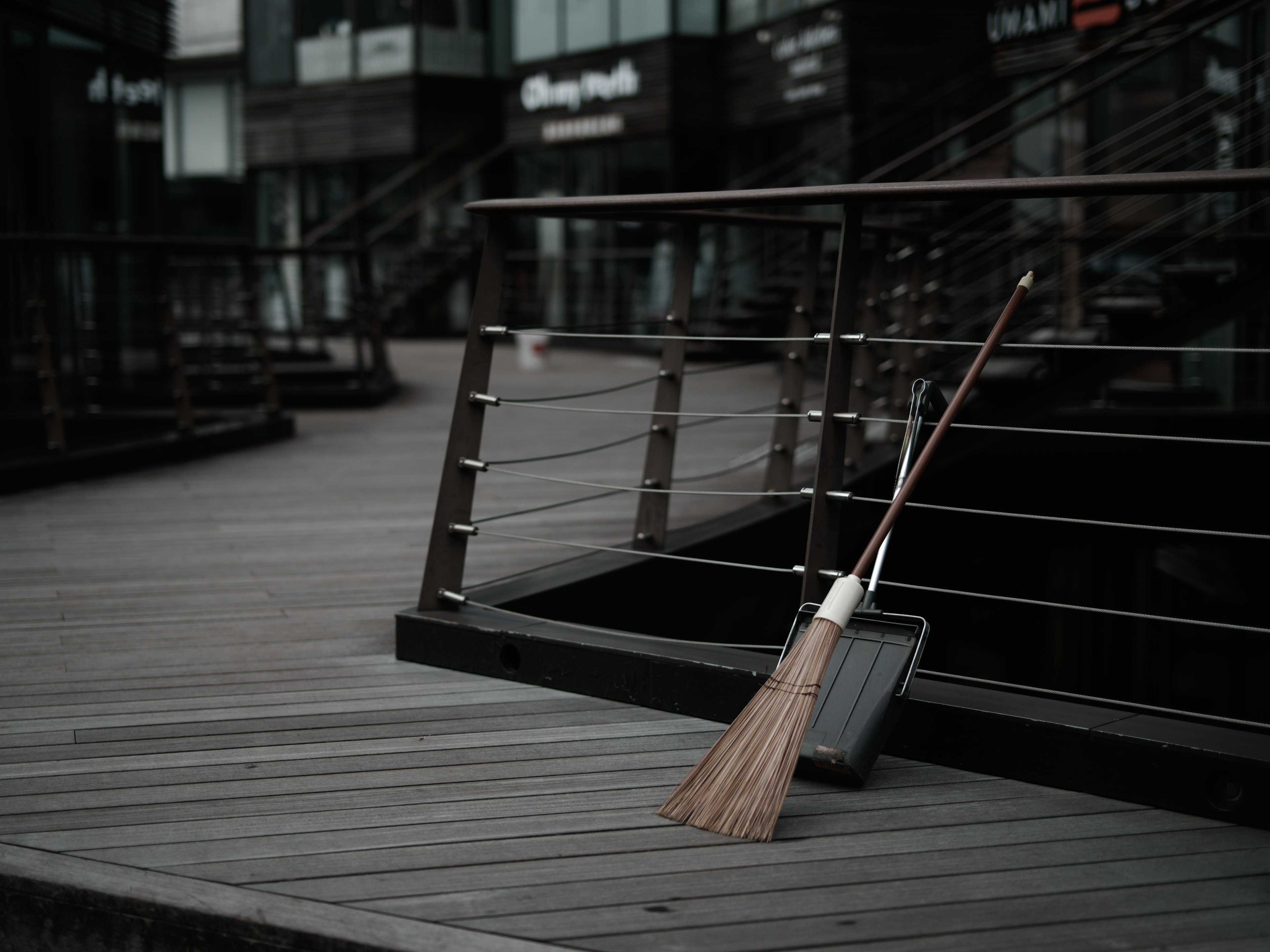 A broom resting on wooden flooring near dark buildings