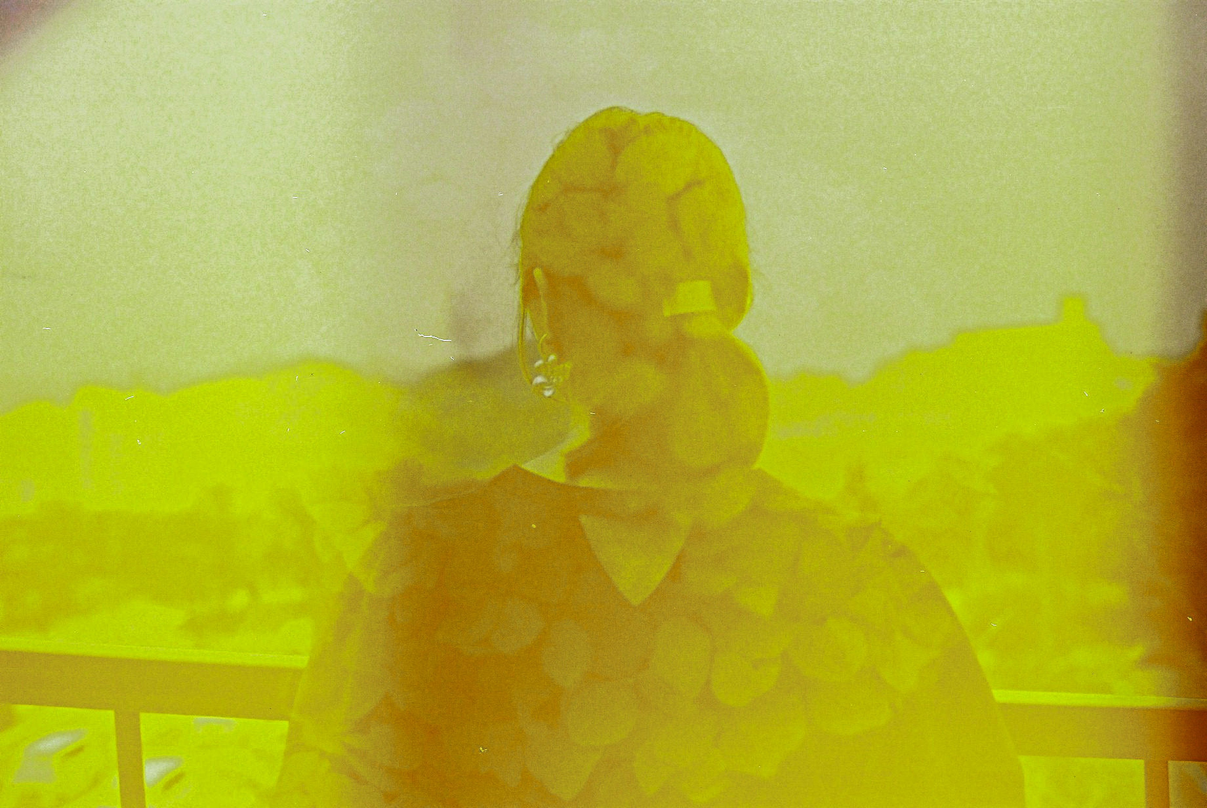 A blurred silhouette of a person against a yellow background