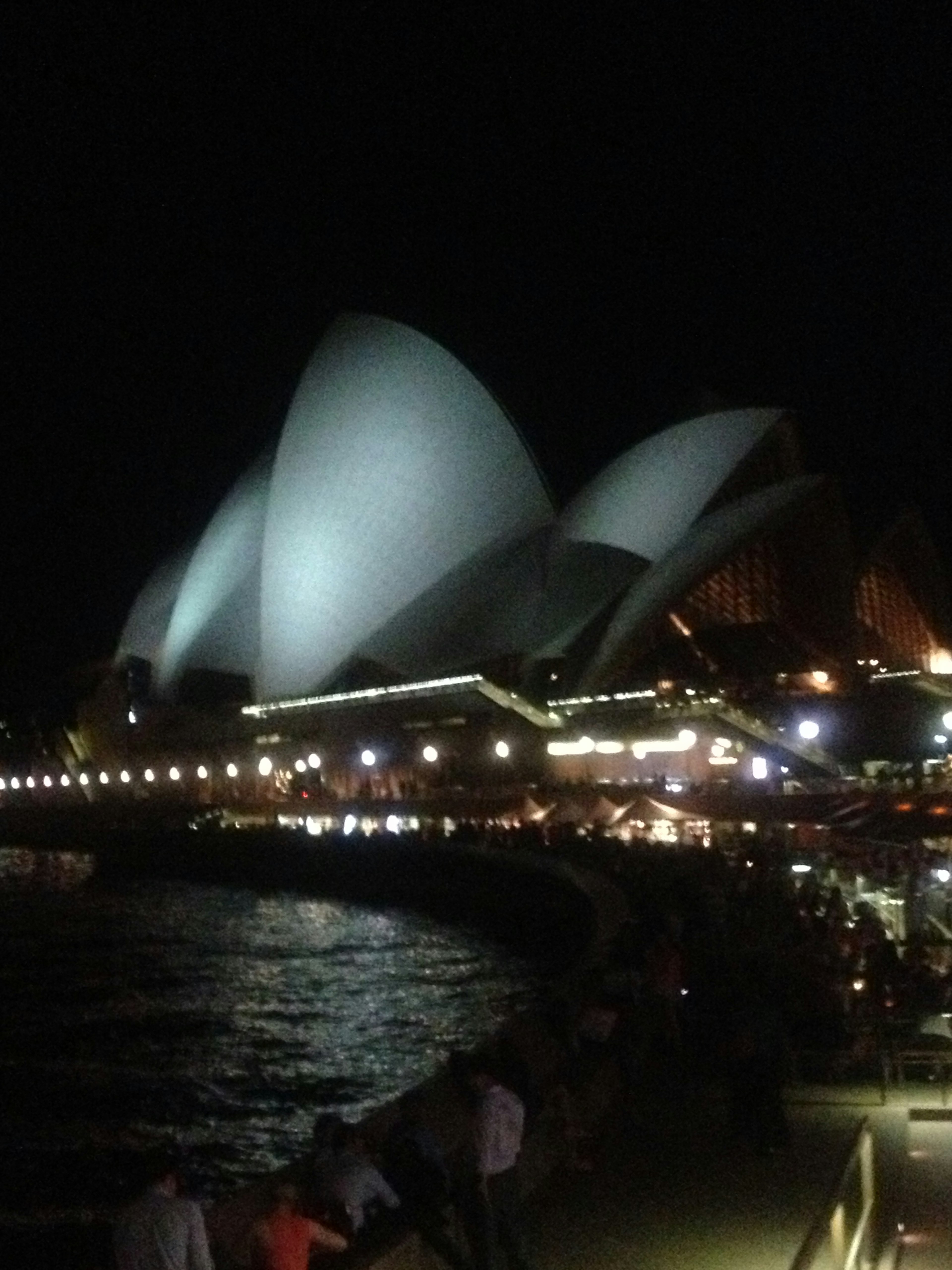 Vista notturna dell'Opera di Sydney con le sue iconiche vele e il lungomare