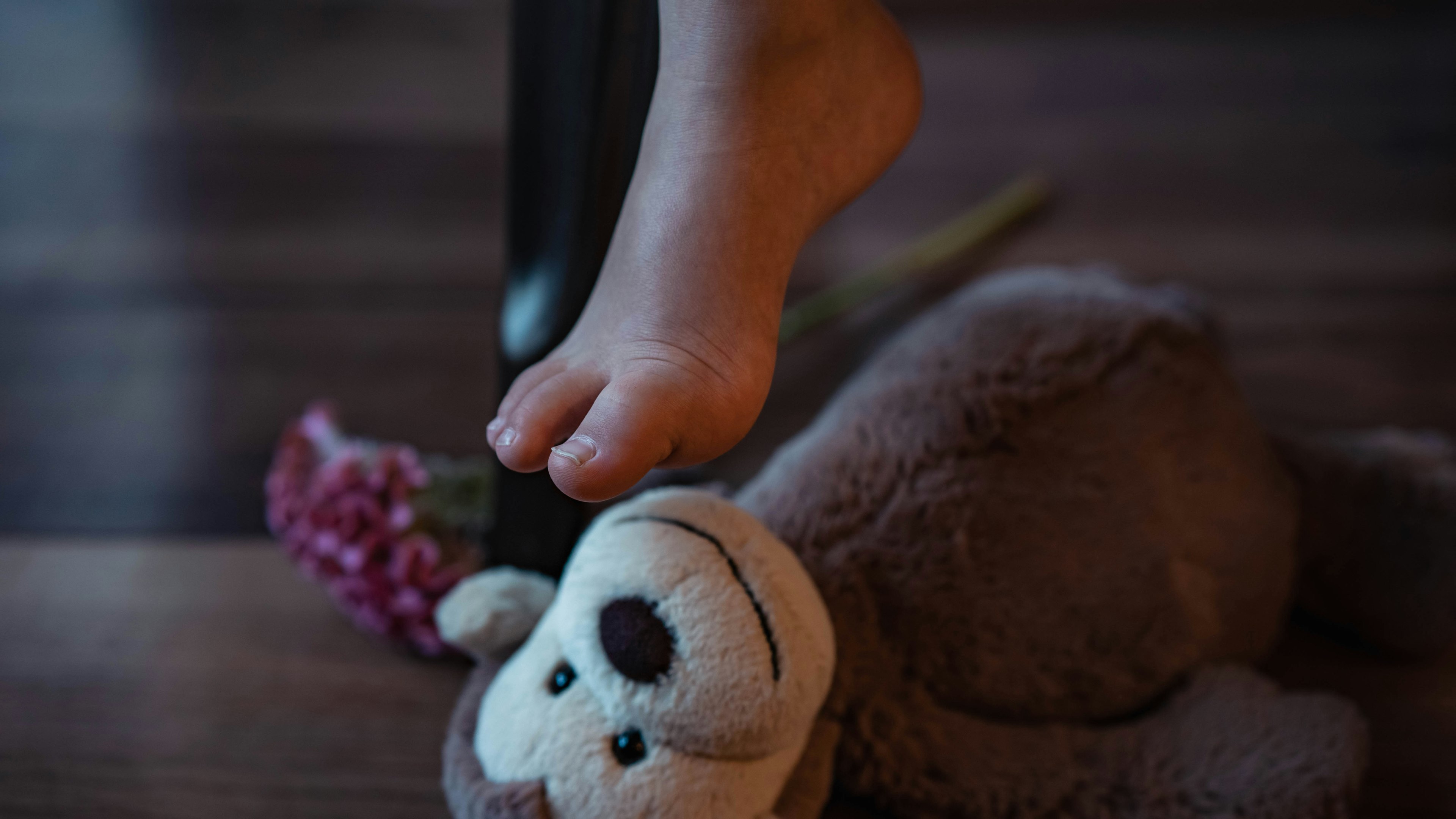 Un pie de niño descansando sobre un juguete de peluche de mono