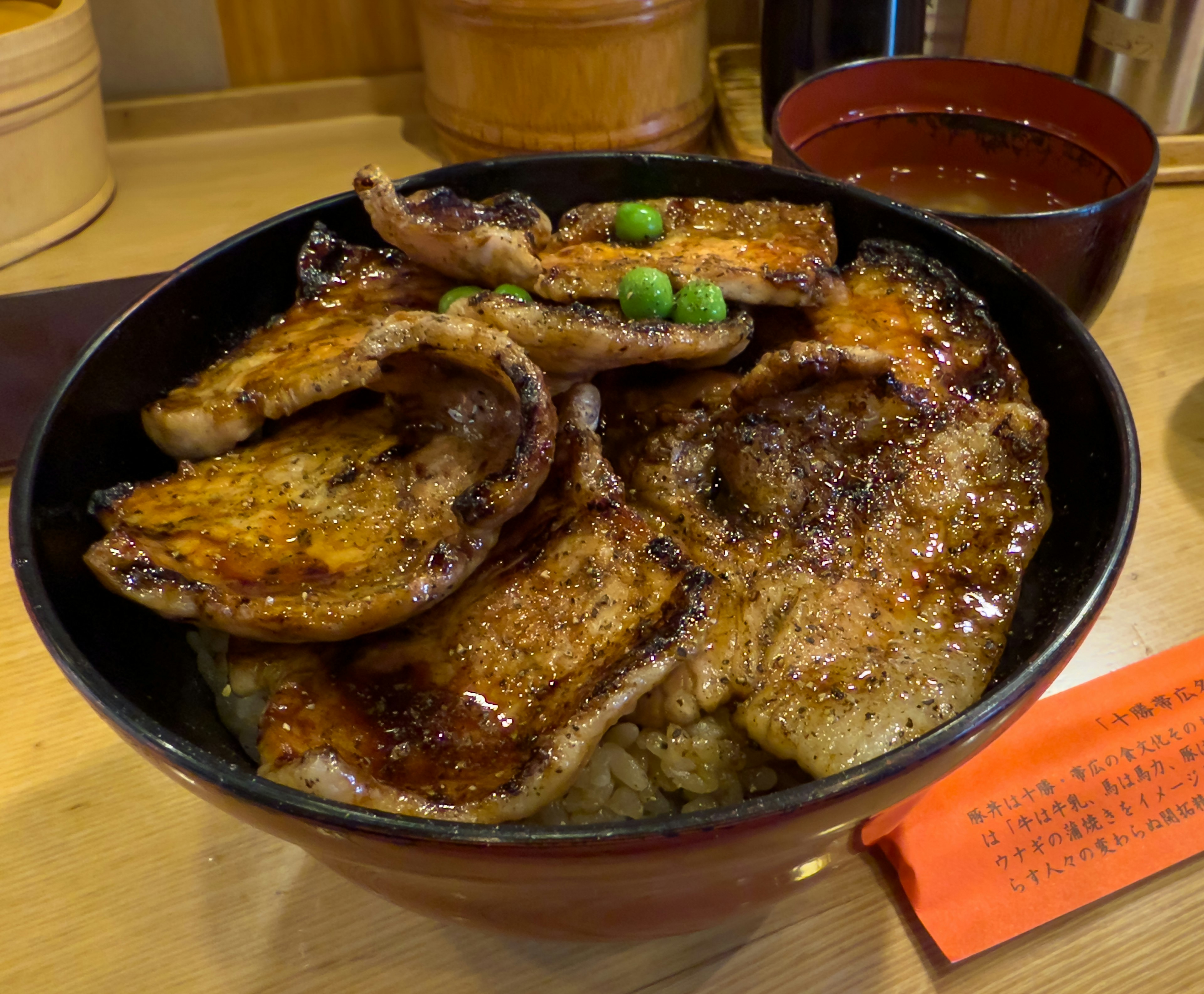 Delicious pork rice bowl featuring grilled pork slices on rice with green peas