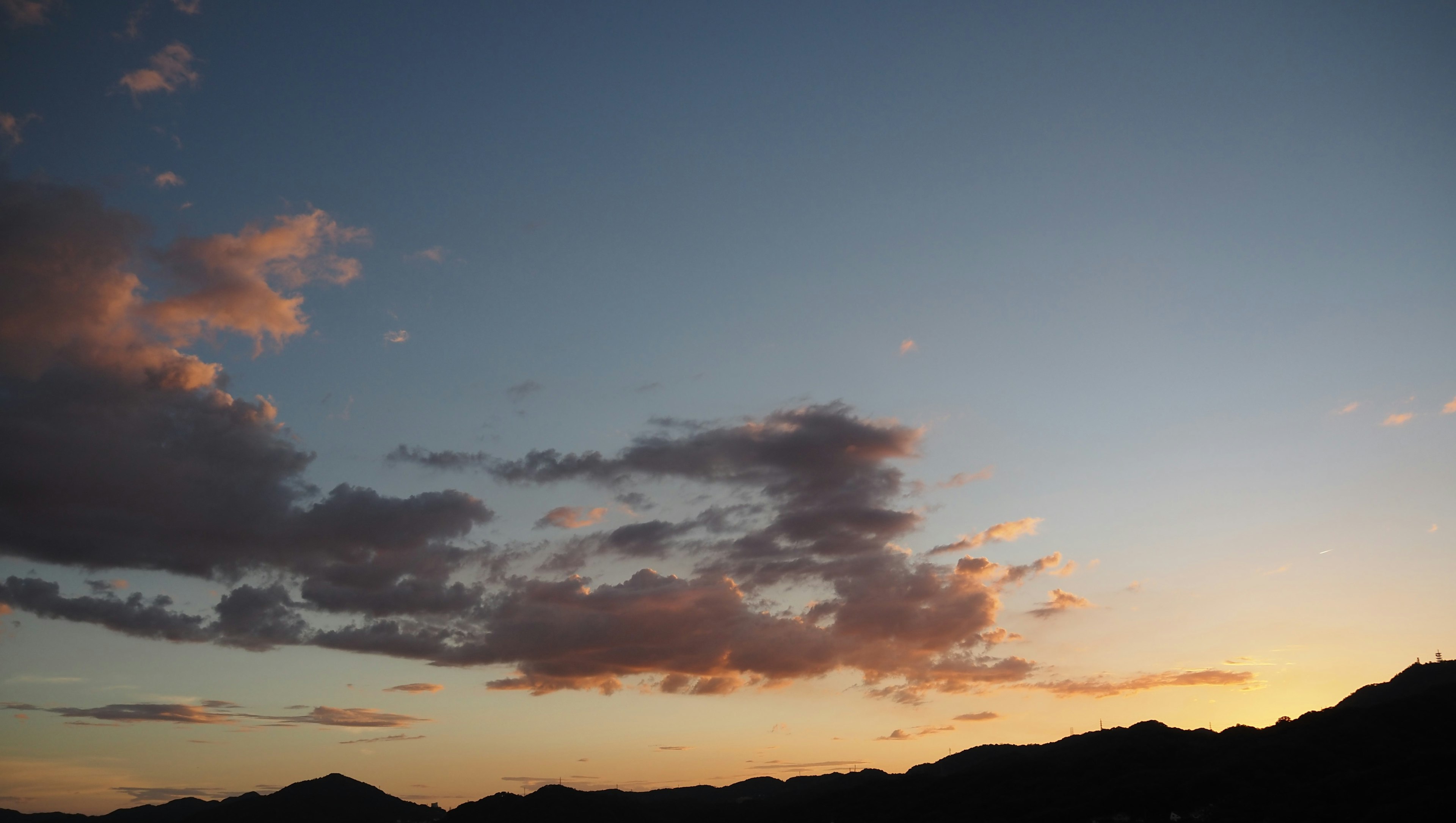 Nuvole in un cielo al tramonto con silhouette di montagne