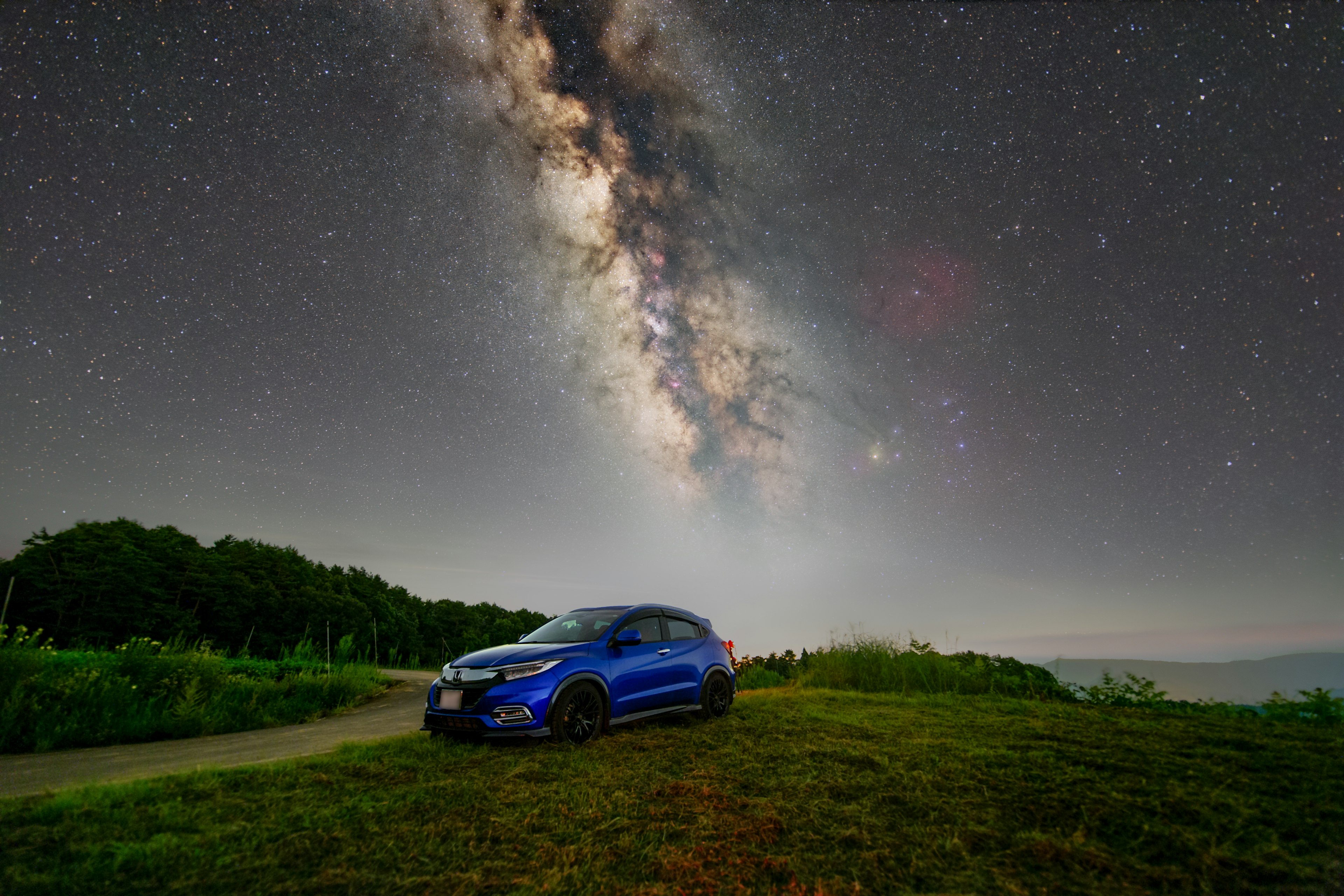 青い車と星空の下に広がる銀河の美しい風景