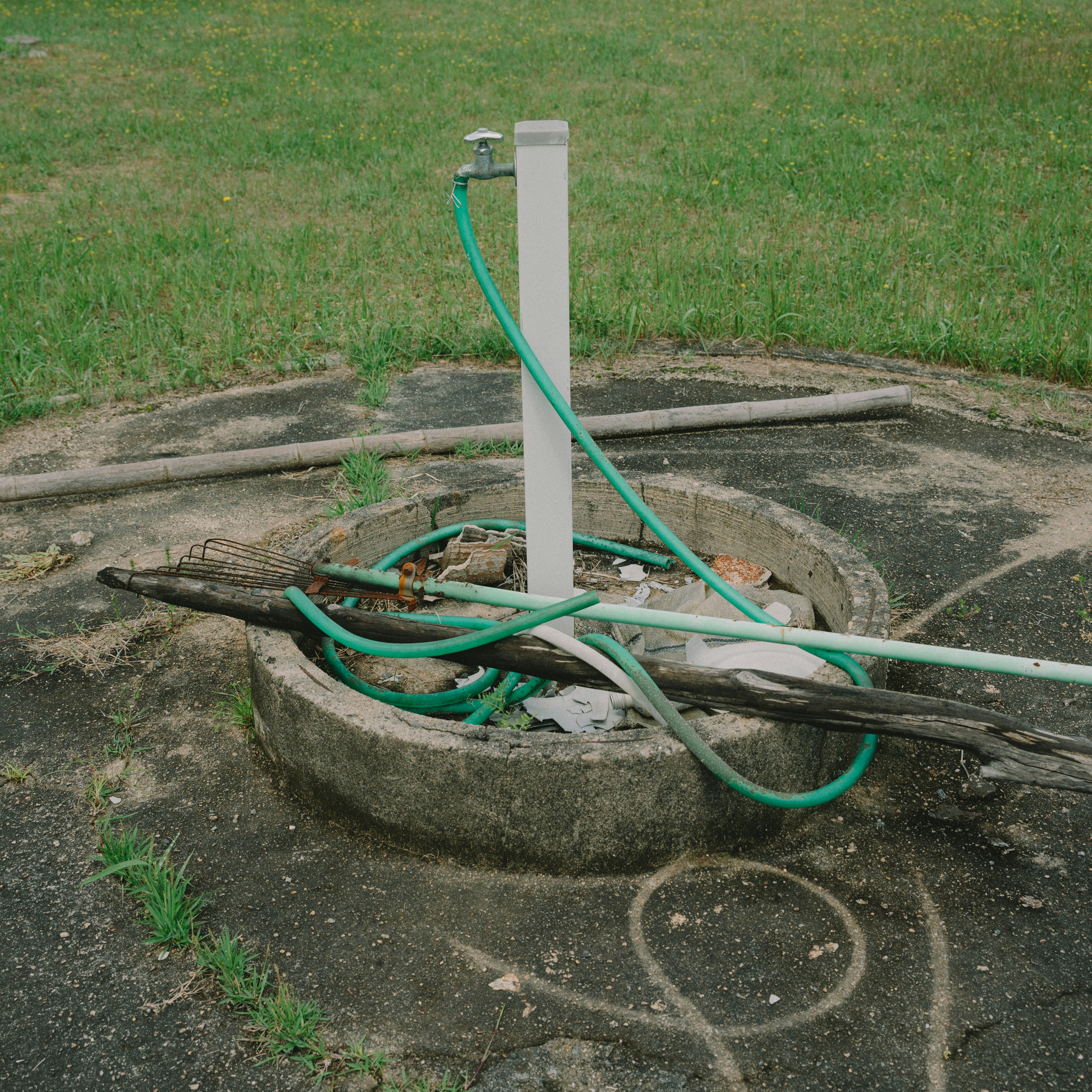 Ein alter Brunnen mit einem grünen Schlauch und Holzplanken darum