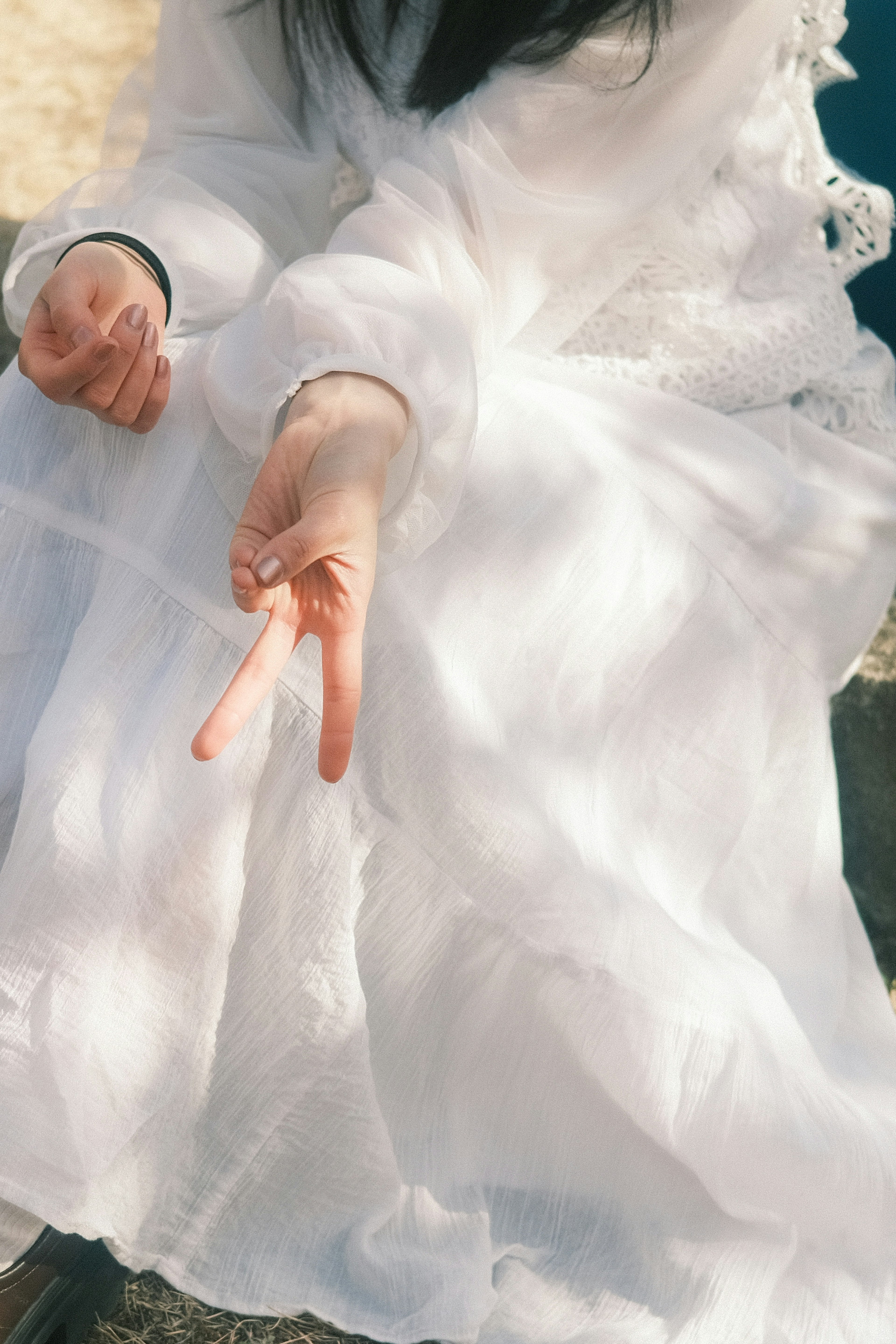 Eine Hand einer Frau in einem weißen Kleid macht ein Friedenszeichen