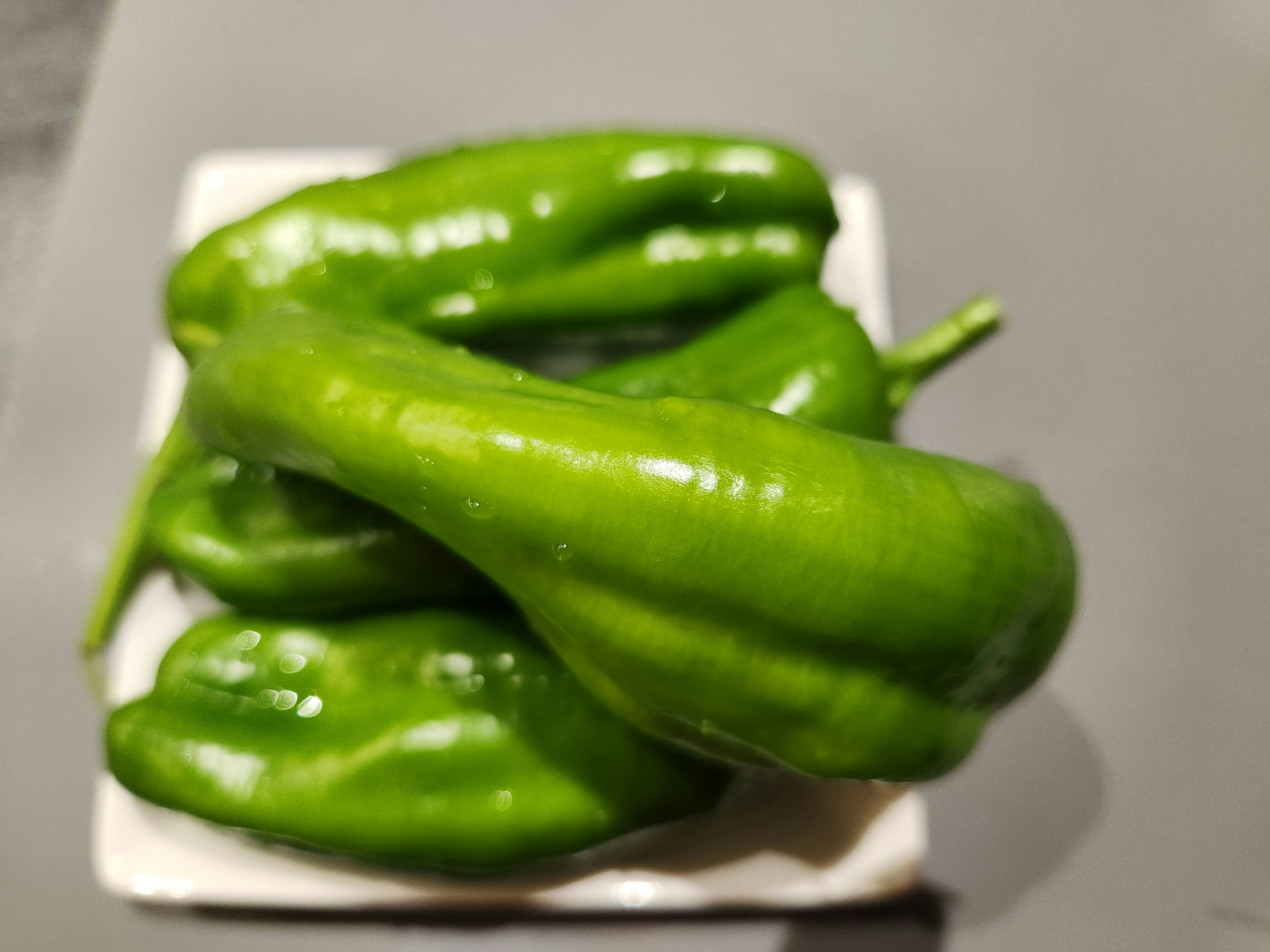 Un grupo de pimientos verdes en un plato blanco