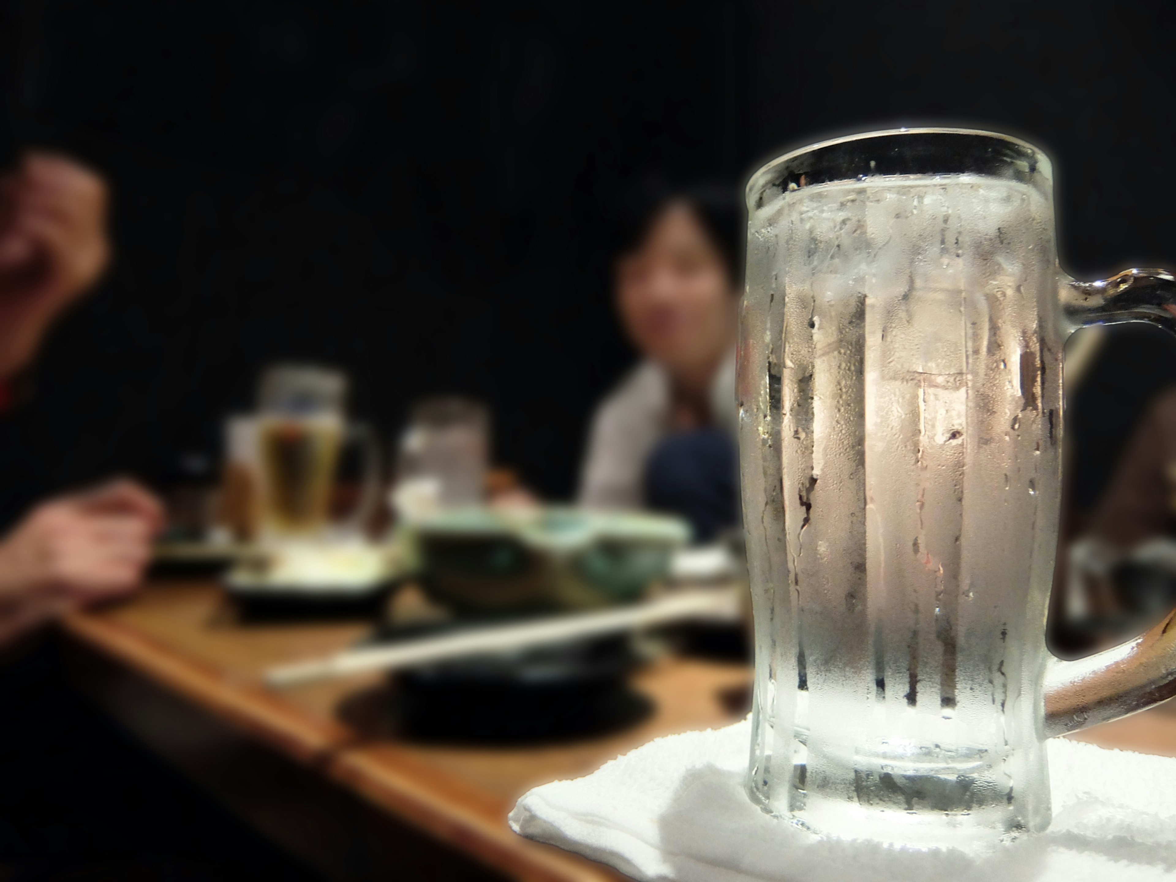 Frosted Glas Bier mit verschwommenen Menschen im Hintergrund