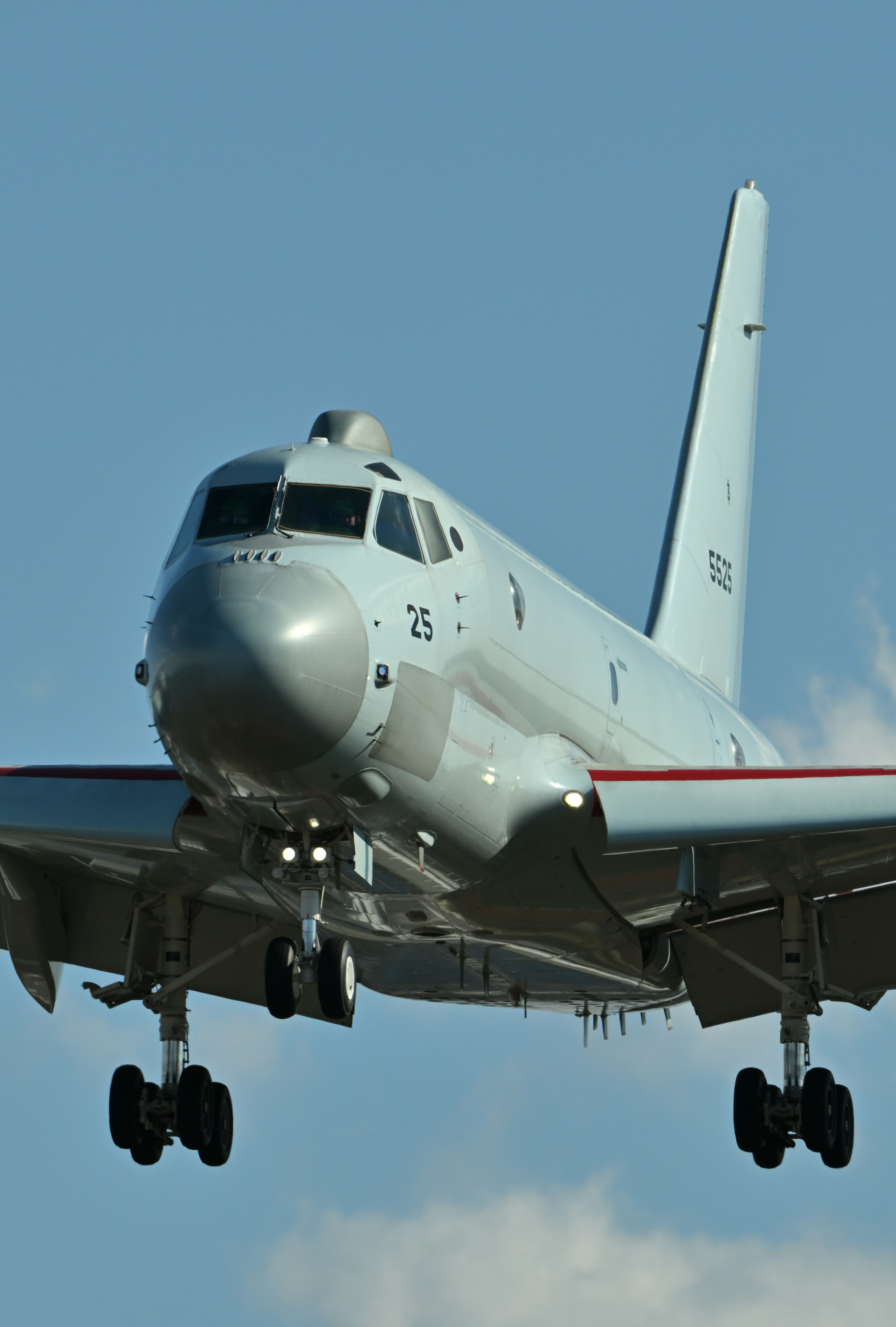 Front view of an aircraft in flight featuring a white fuselage and red stripe