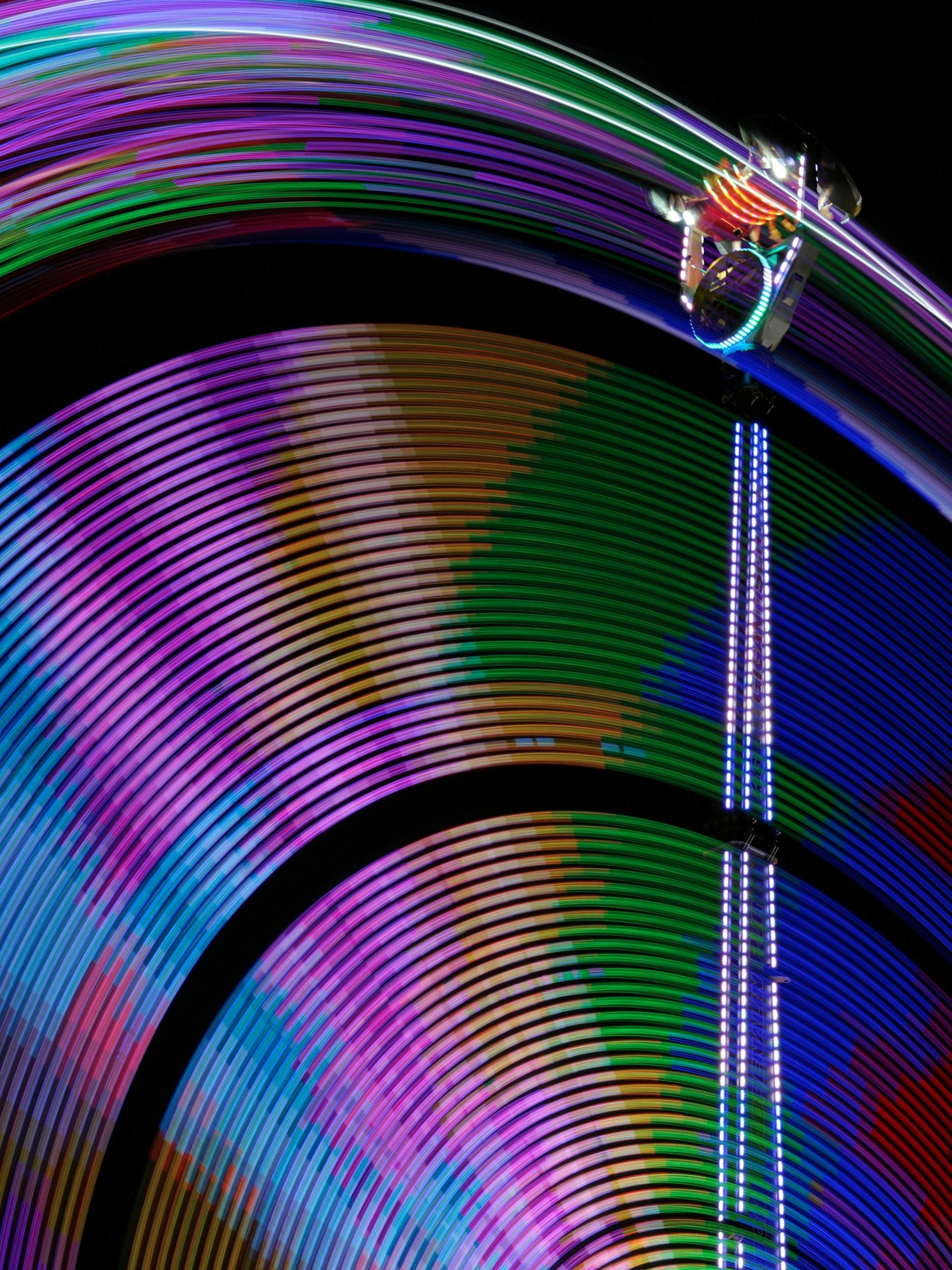 Colorful circular light patterns with a Ferris wheel in the upper part