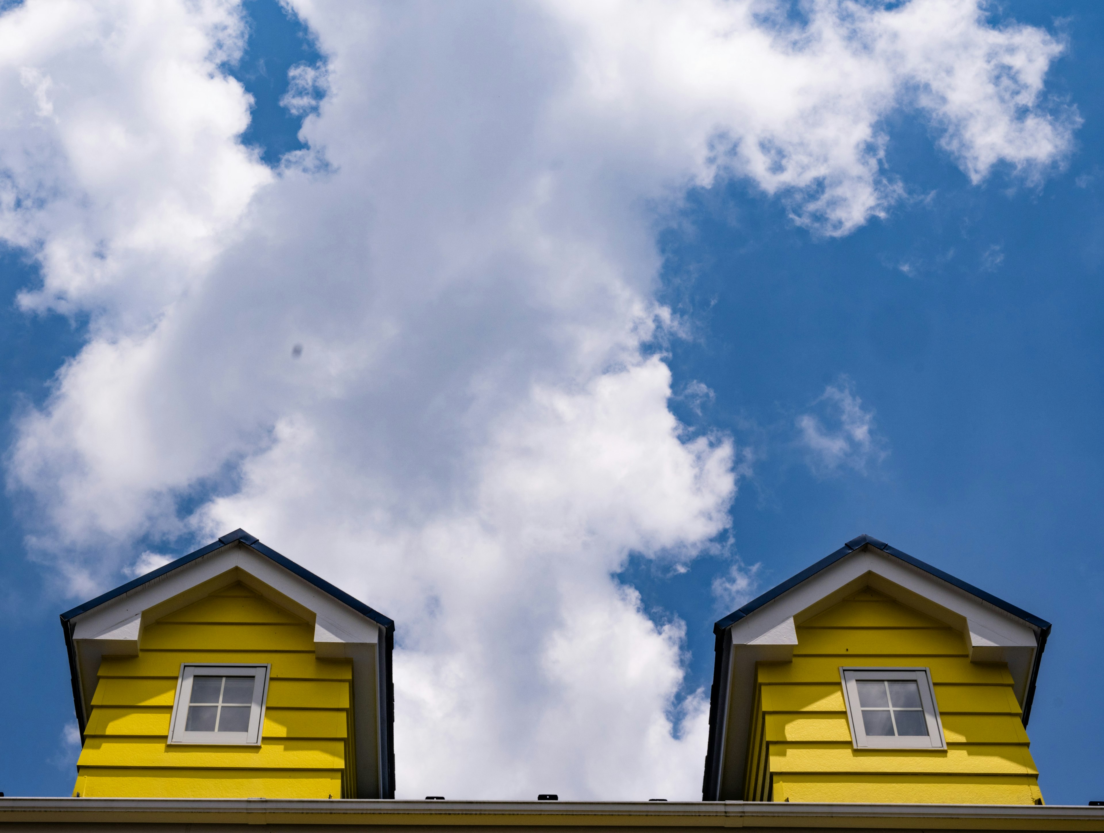 Dos ventanas en el techo amarillo bajo un cielo azul