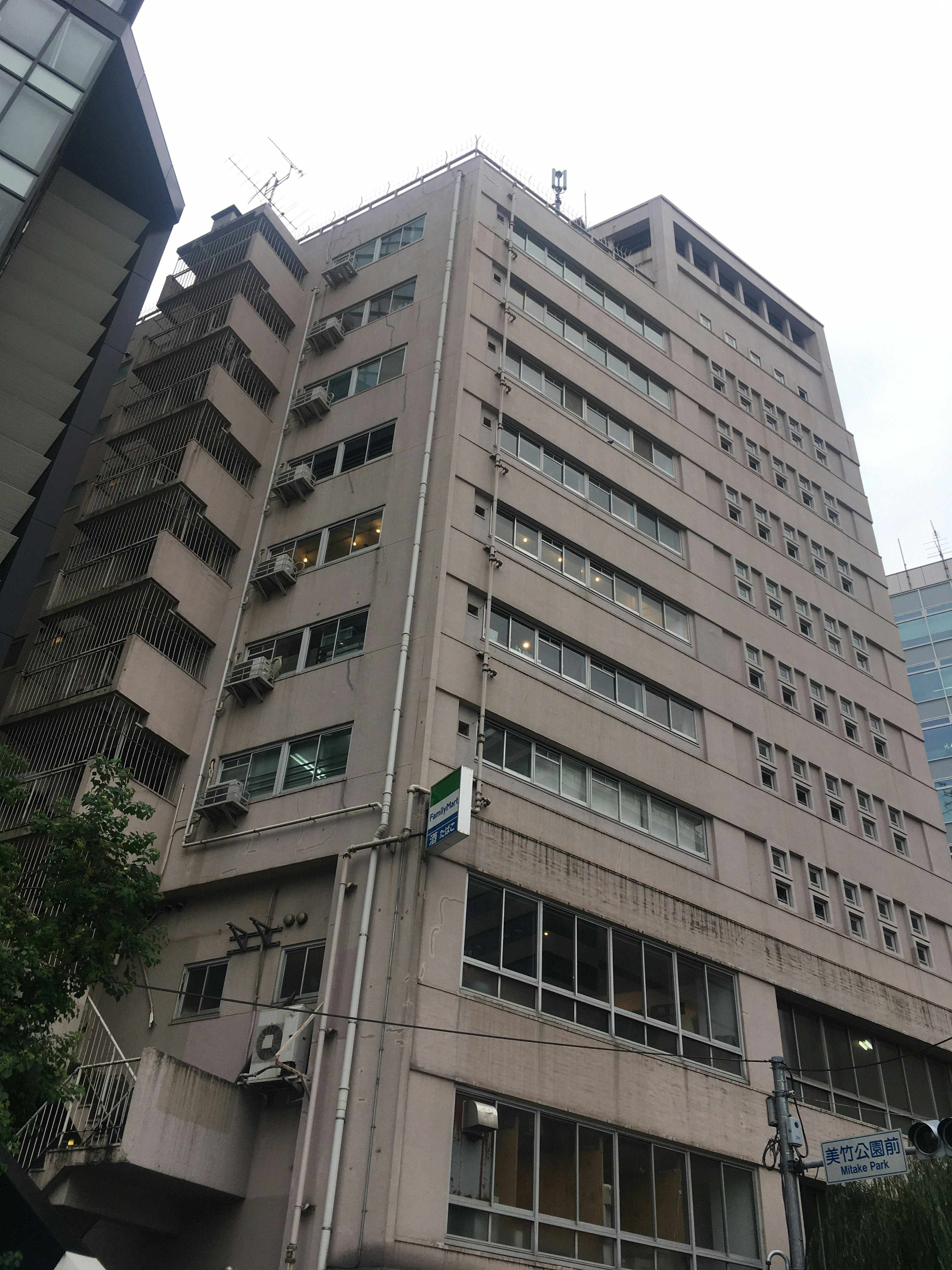 Exterior of a high-rise building with gray facade multiple windows surrounded by other buildings