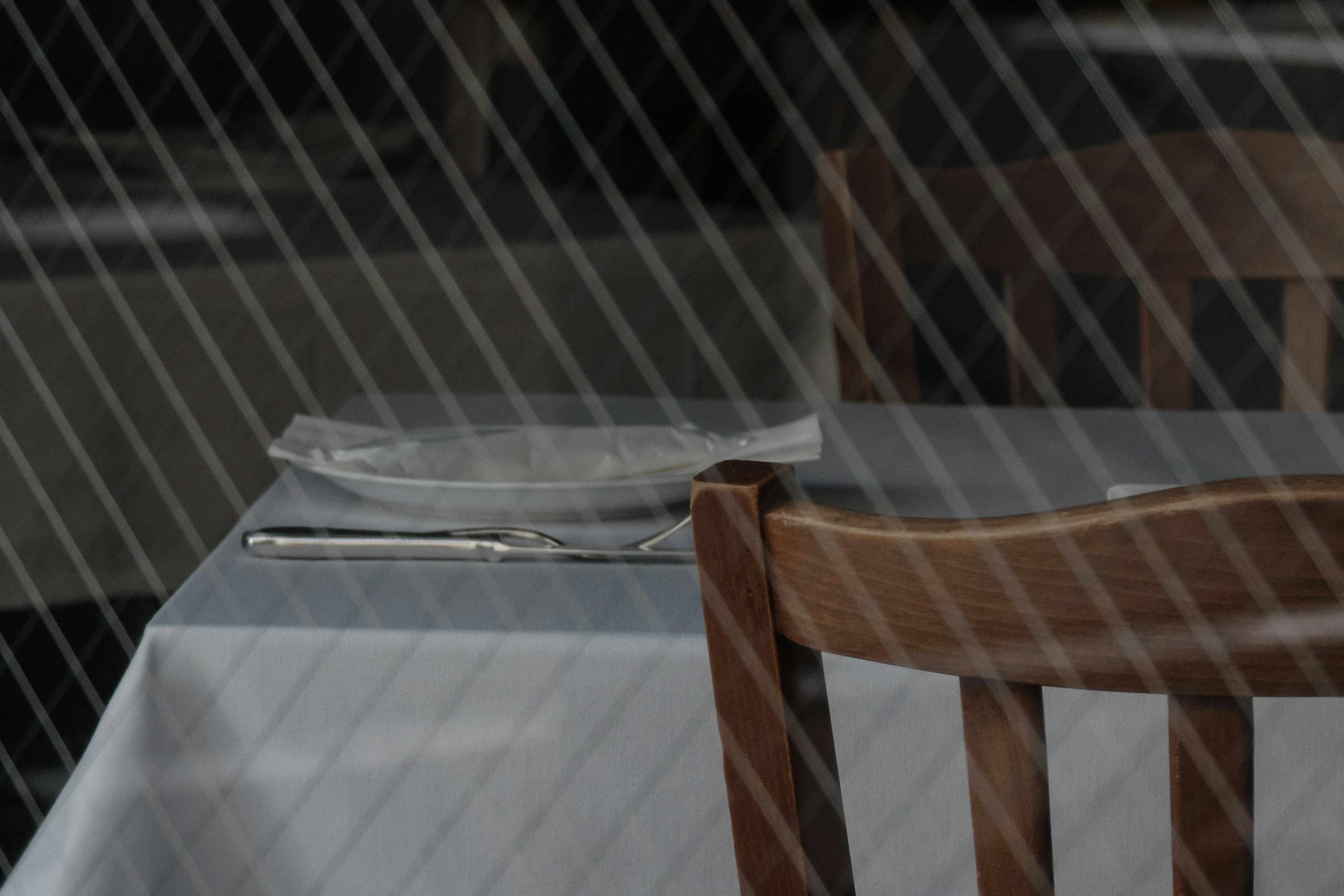 Vista interna di un ristorante con una sedia di legno e un tavolo coperto da una tovaglia bianca