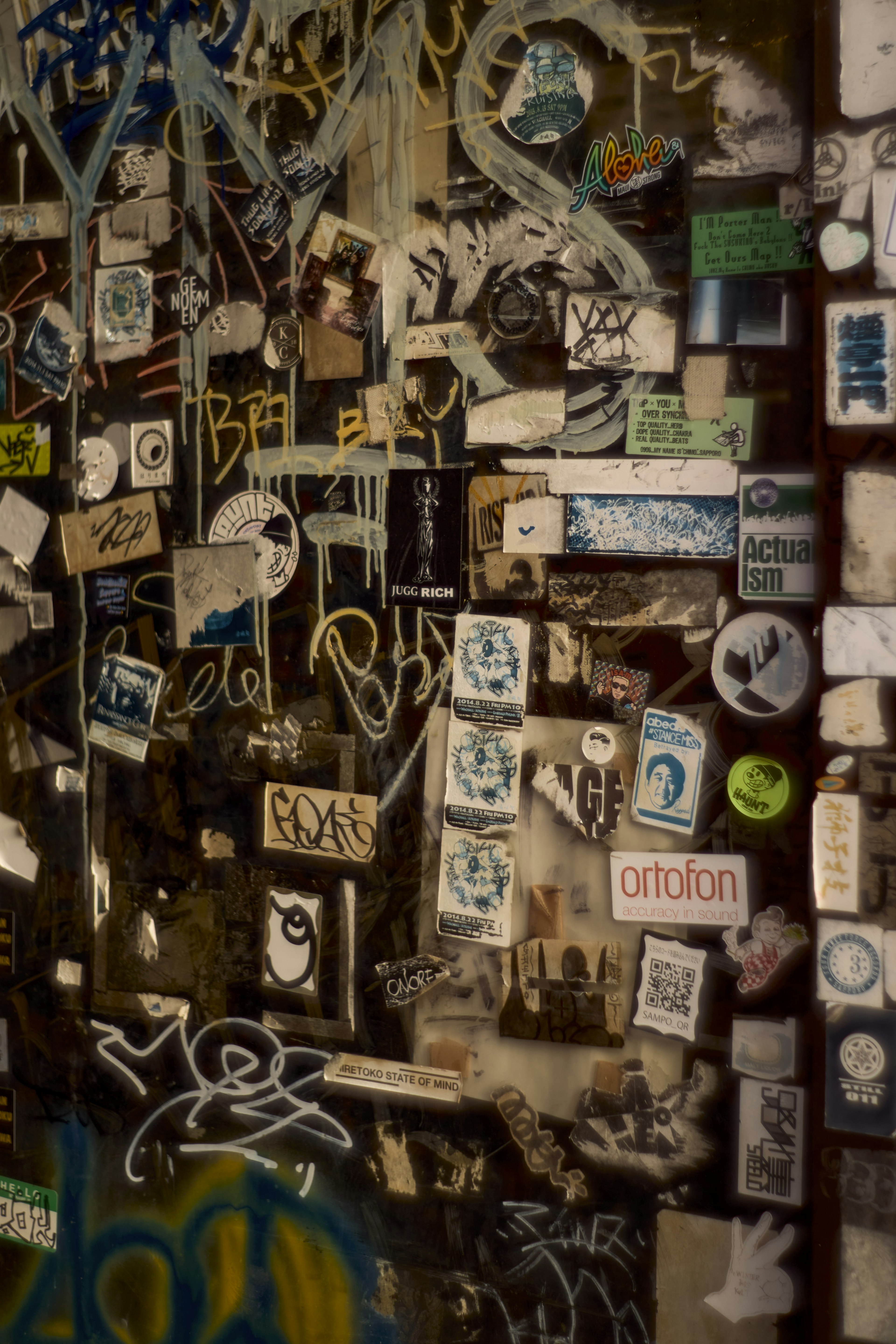 Close-up of a wall covered with various stickers and graffiti