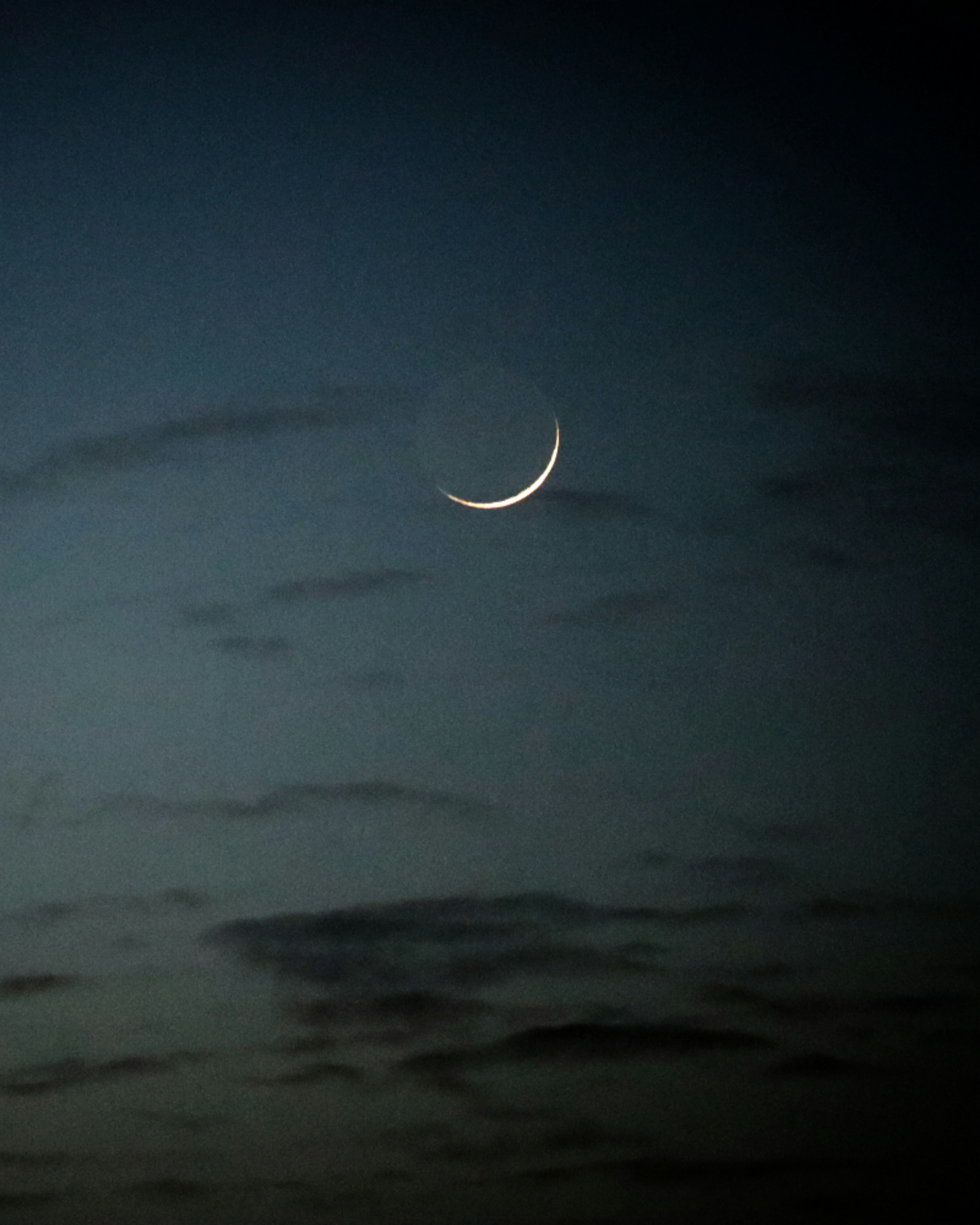 Bulan sabit tipis di langit senja dengan awan