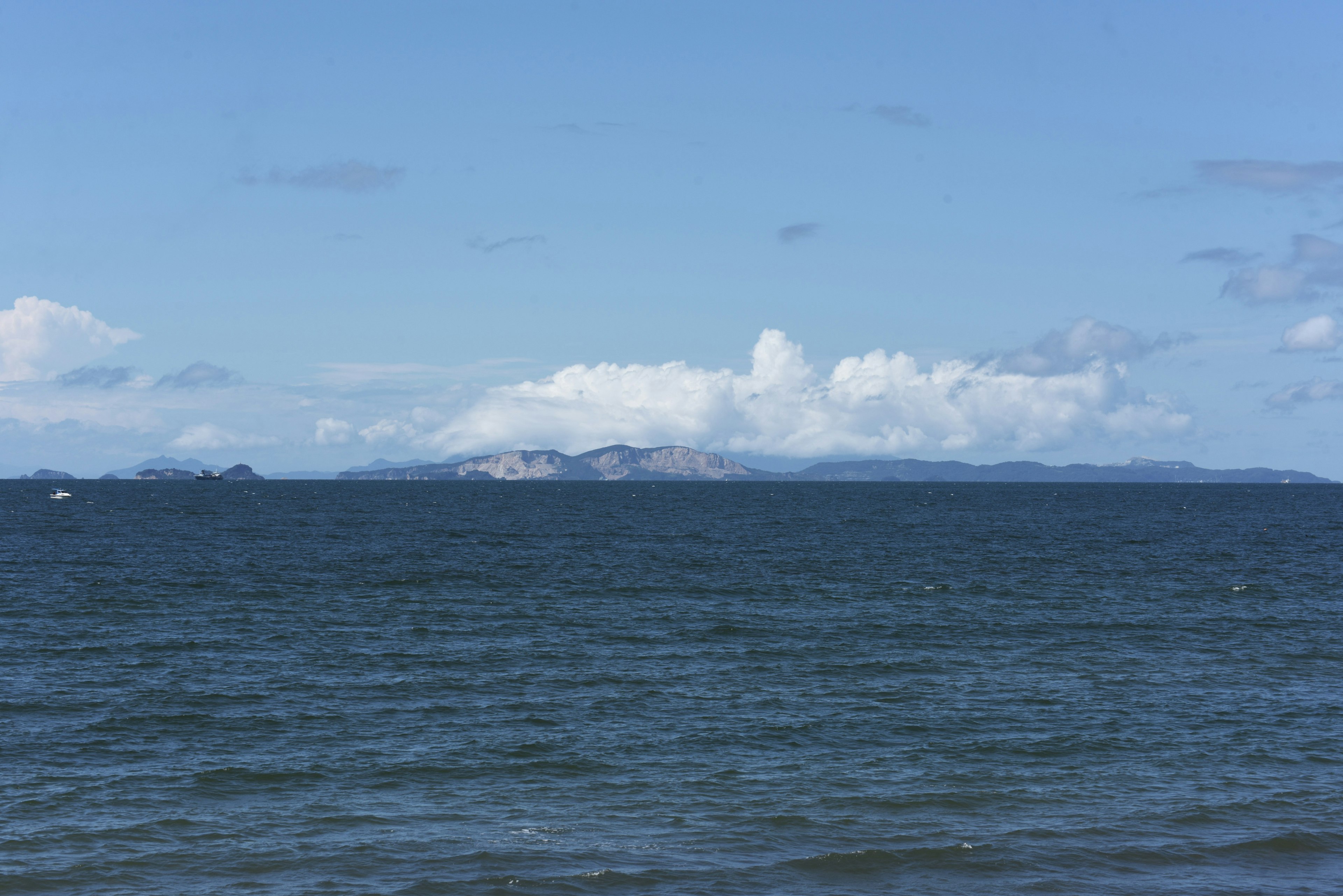 Blick auf den blauen Ozean mit fernen Inseln und Wolken