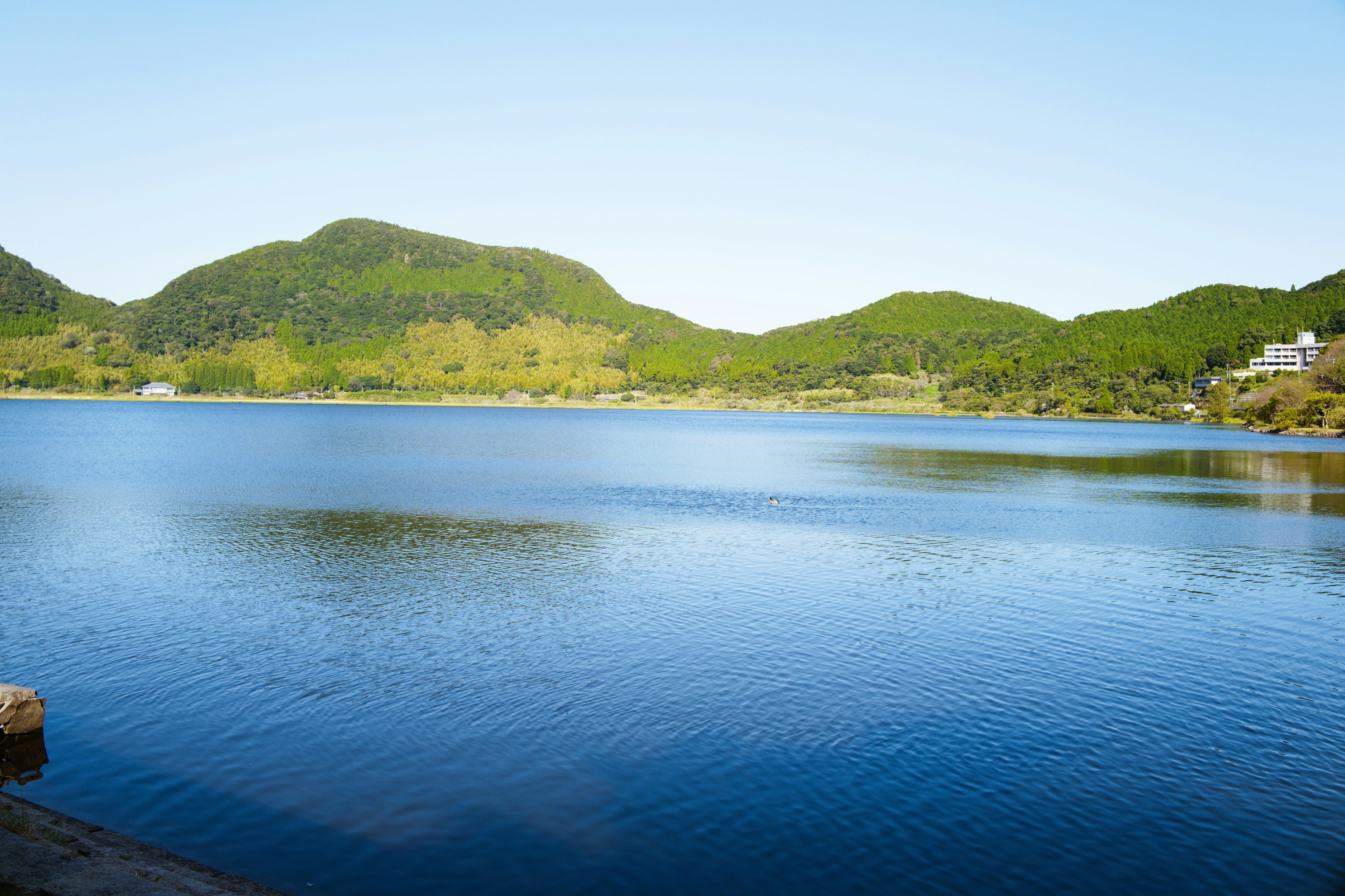 Vue panoramique d'un lac bleu entouré de collines vertes