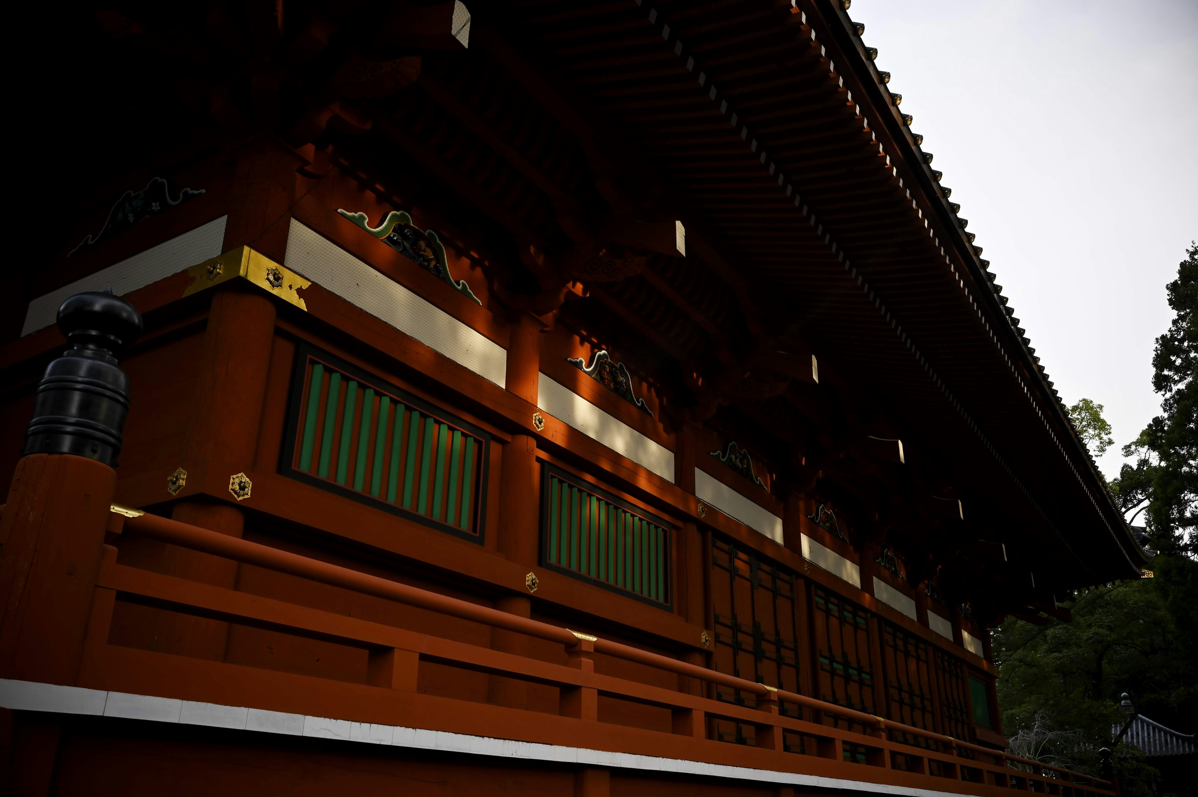 Part of a traditional Japanese shrine featuring red walls and green windows