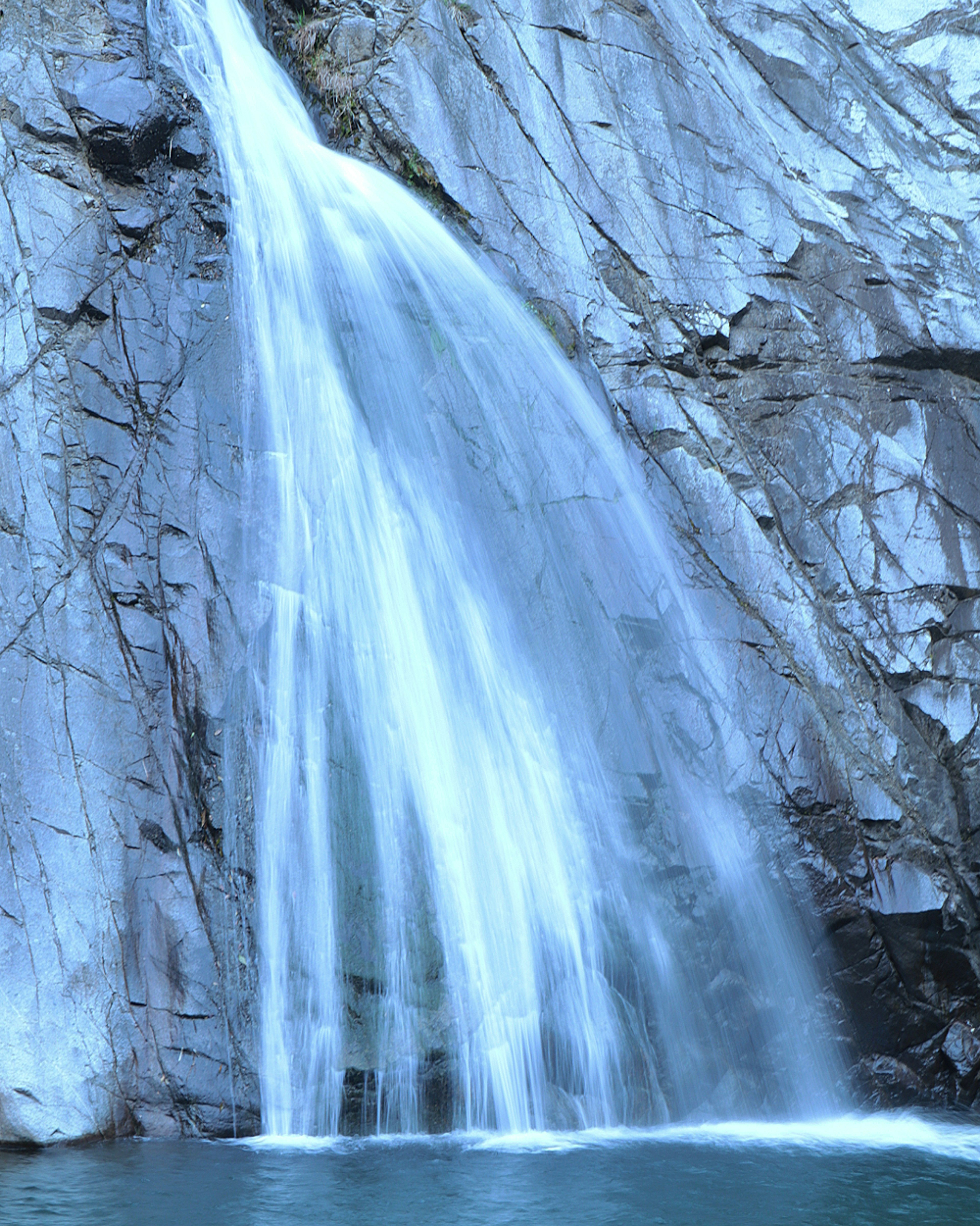 Ein schöner Wasserfall, der von felsigen Klippen mit einem blauen Farbton herabstürzt