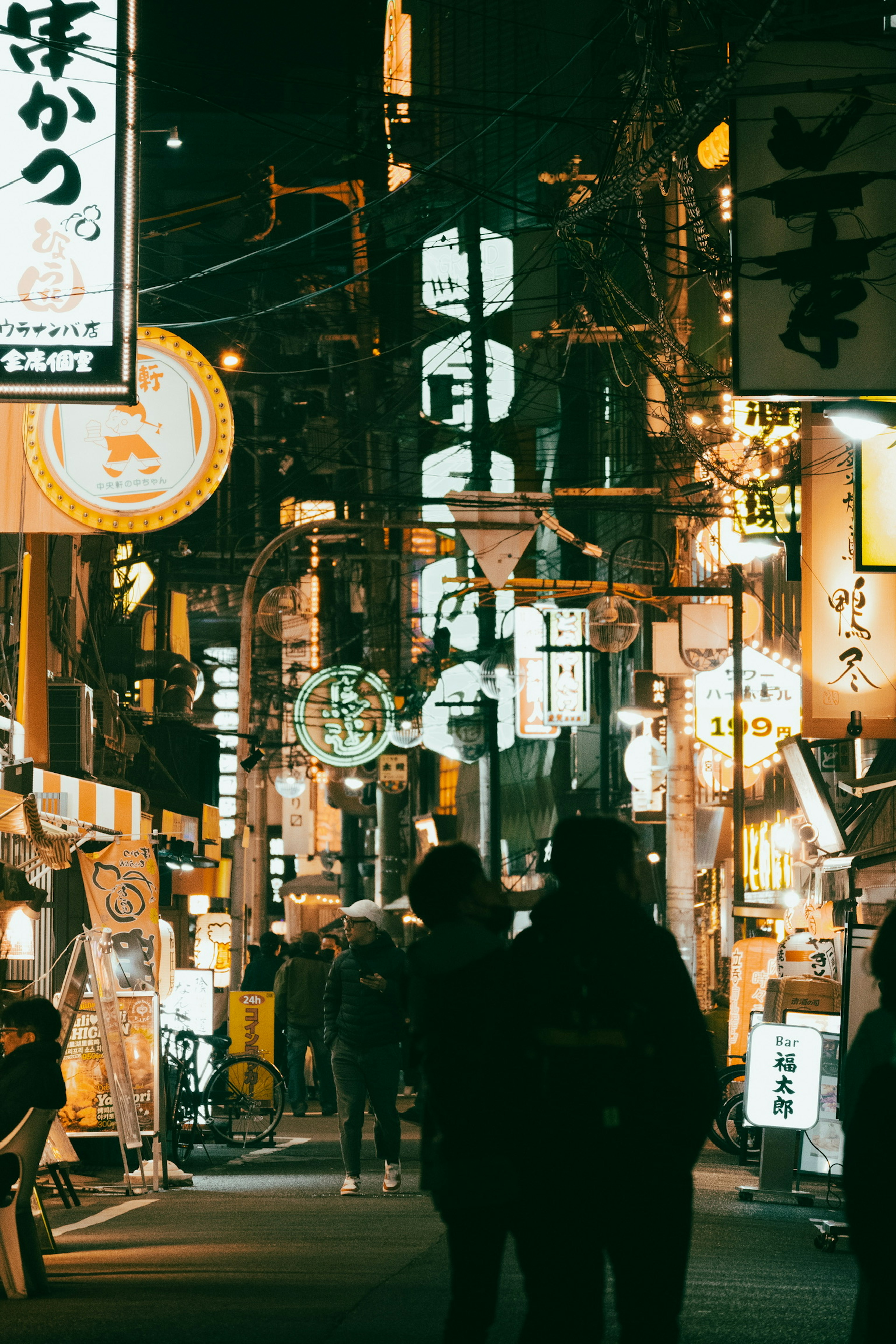 Calle japonesa concurrida de noche con letreros iluminados y personas