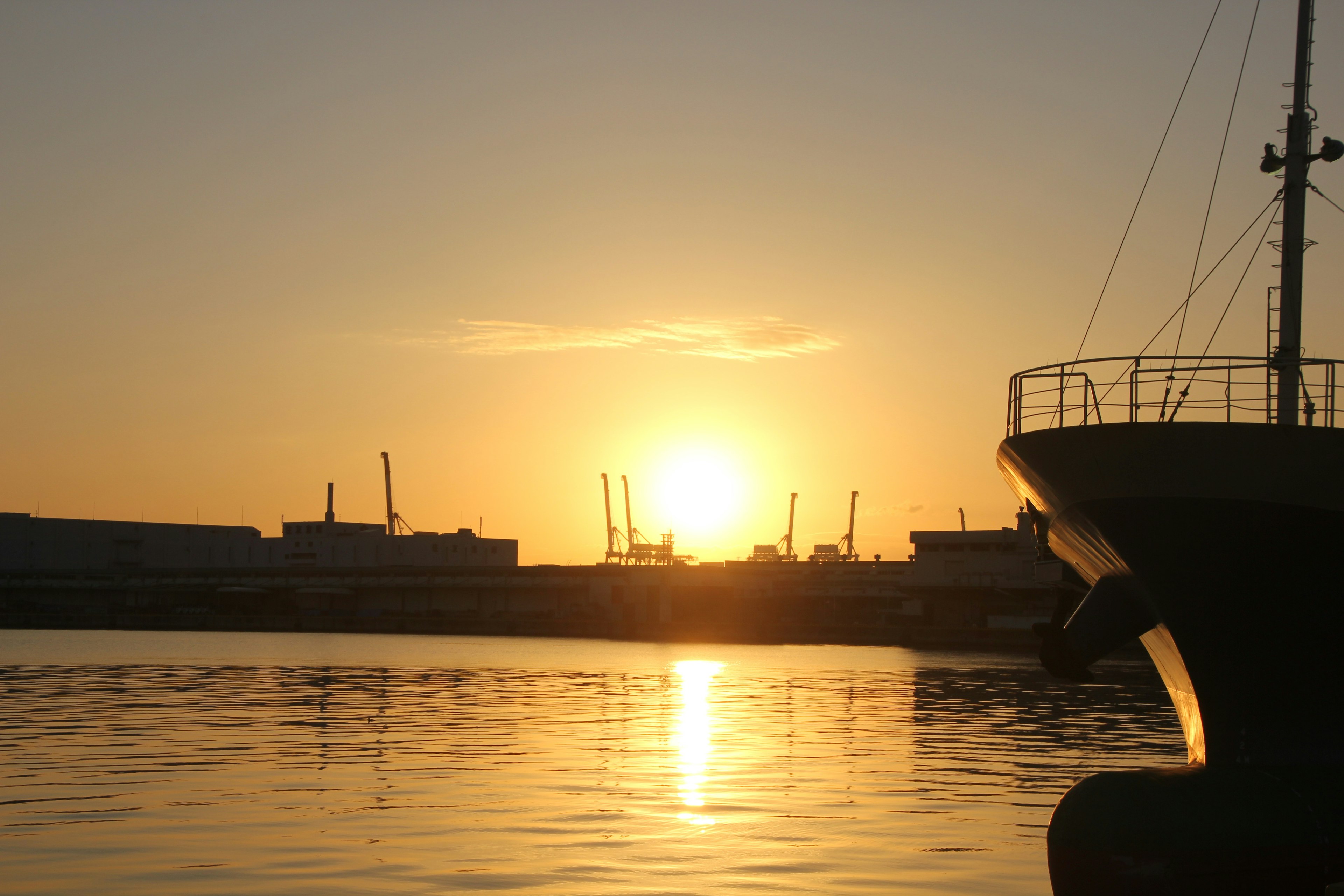 Hafenansicht bei Sonnenuntergang mit Spiegelungen im Wasser und einem Boot