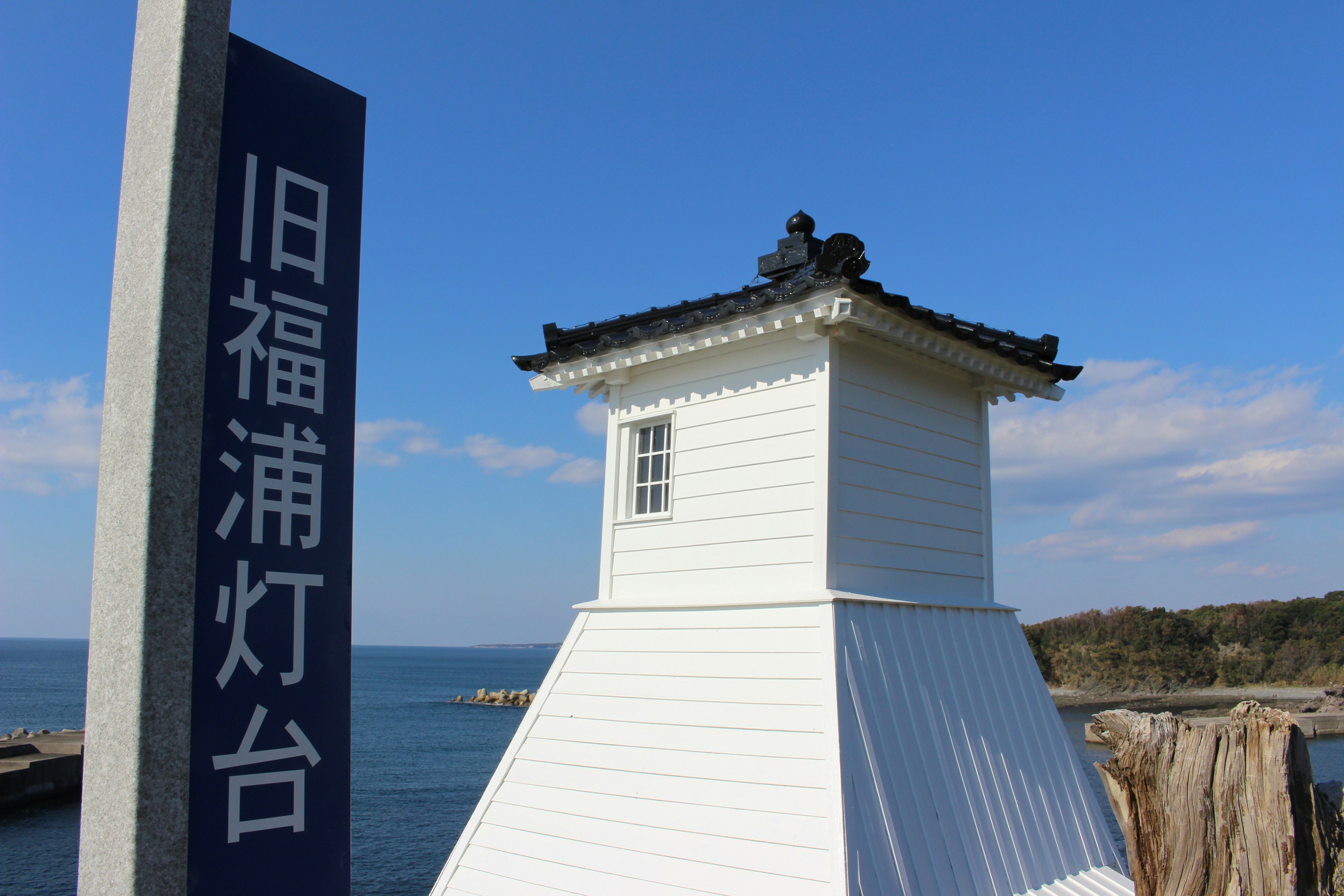 Viejo faro de Fukura con estructura blanca y mar azul