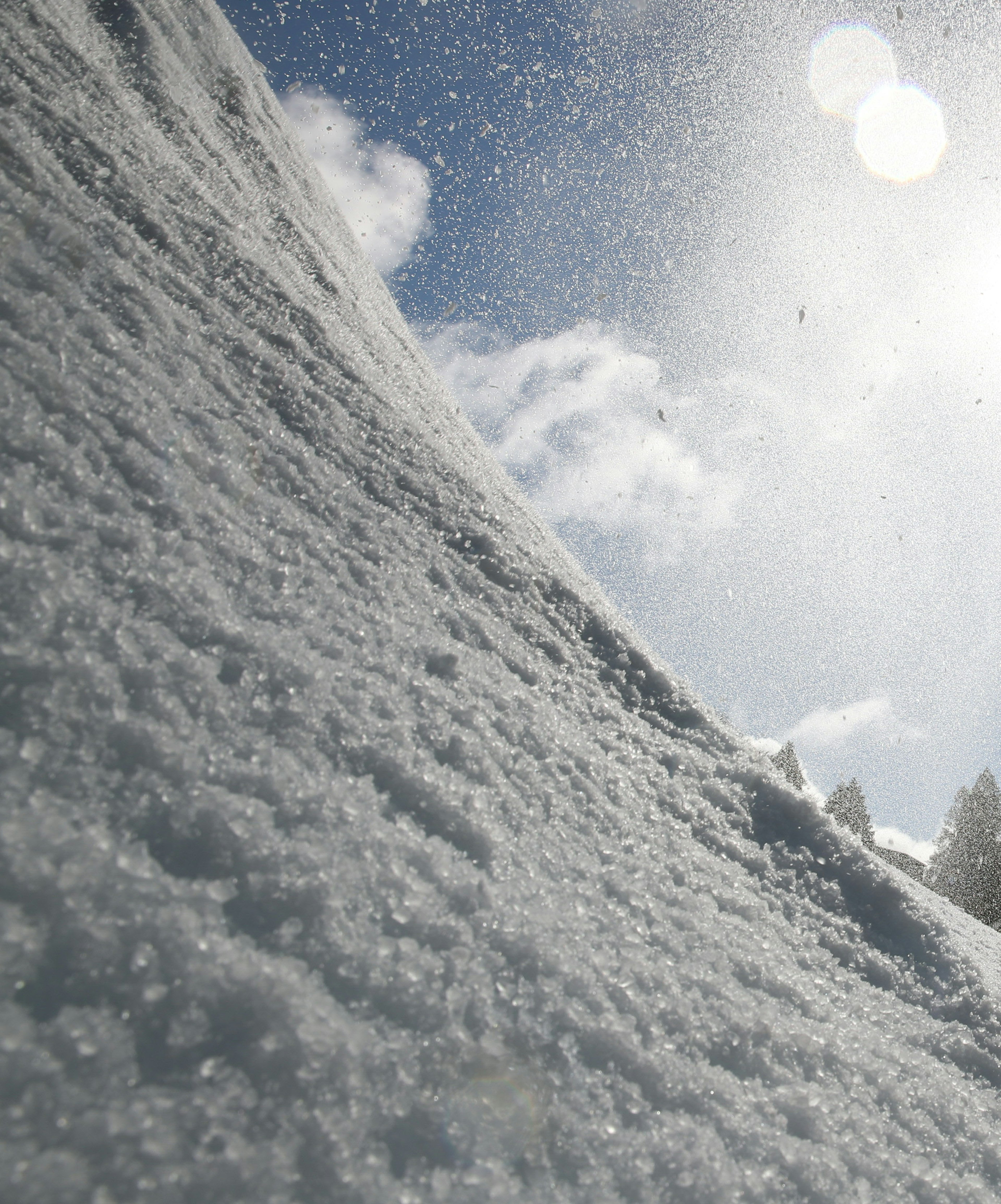 Snowy slope with snowflakes and sunlight against a clear sky