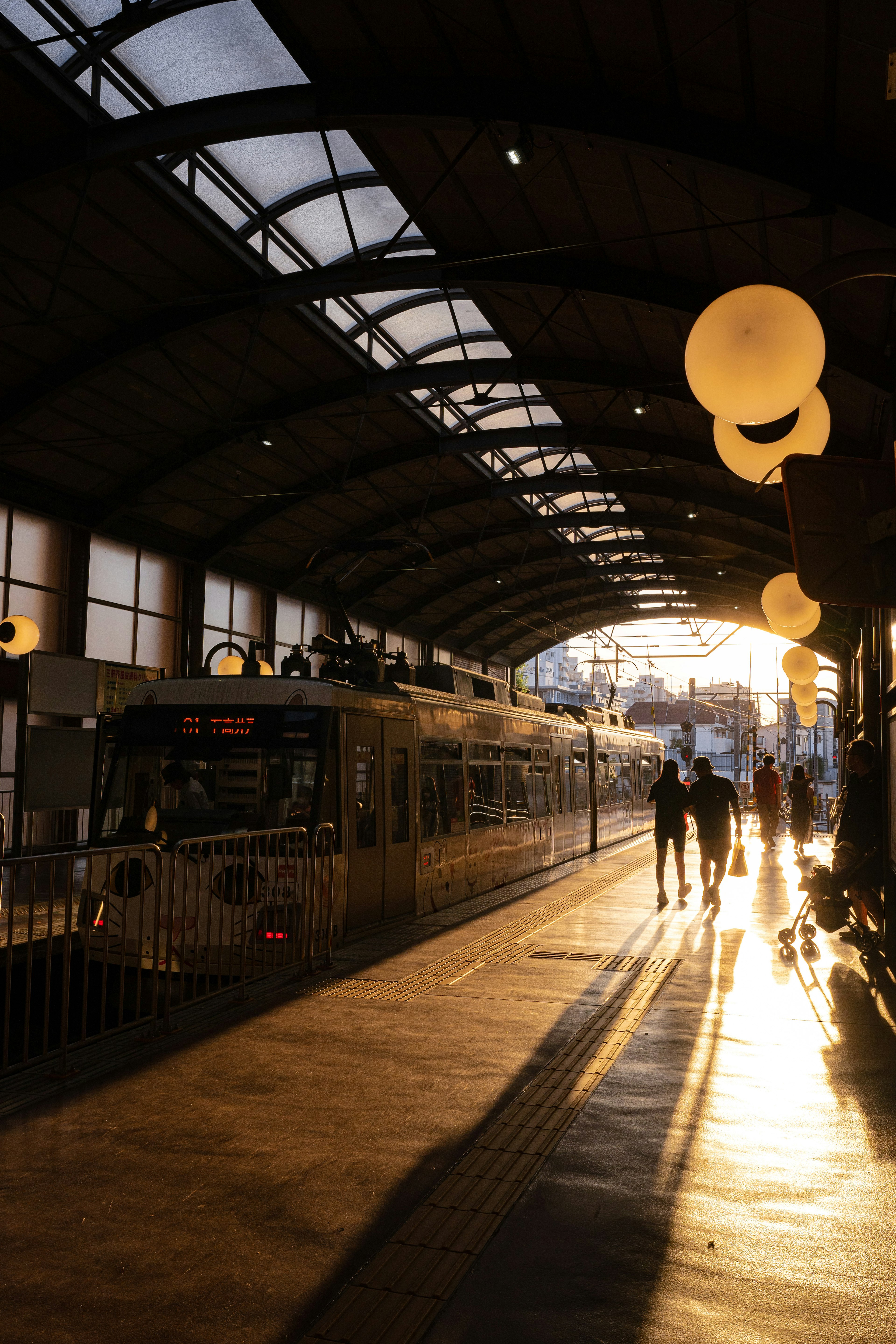 เงาของคนเดินในสถานีรถไฟในช่วงพระอาทิตย์ตกพร้อมรถไฟที่อยู่บนชานชาลา