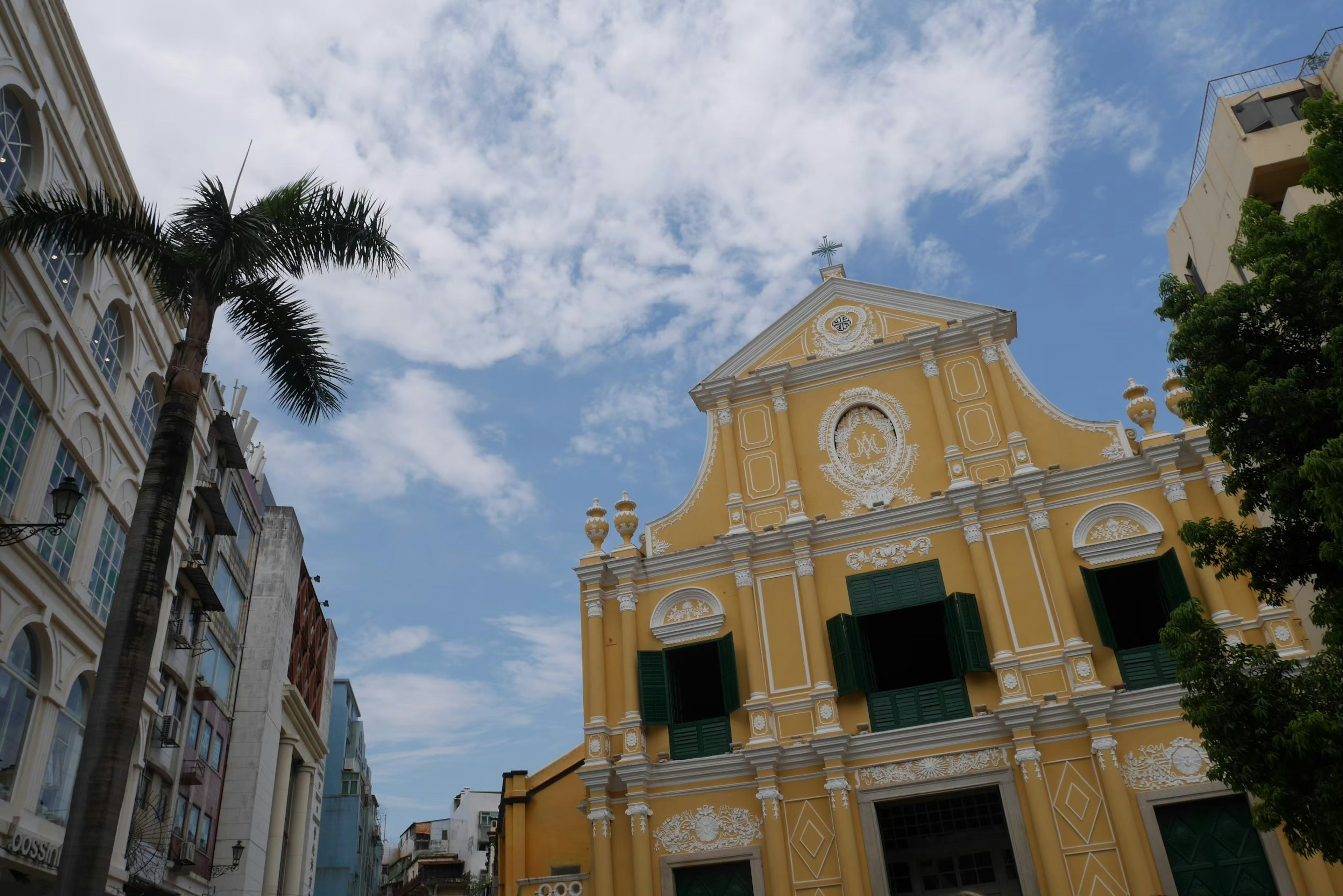 Vista di strada con un edificio giallo e finestre verdi sotto un cielo blu