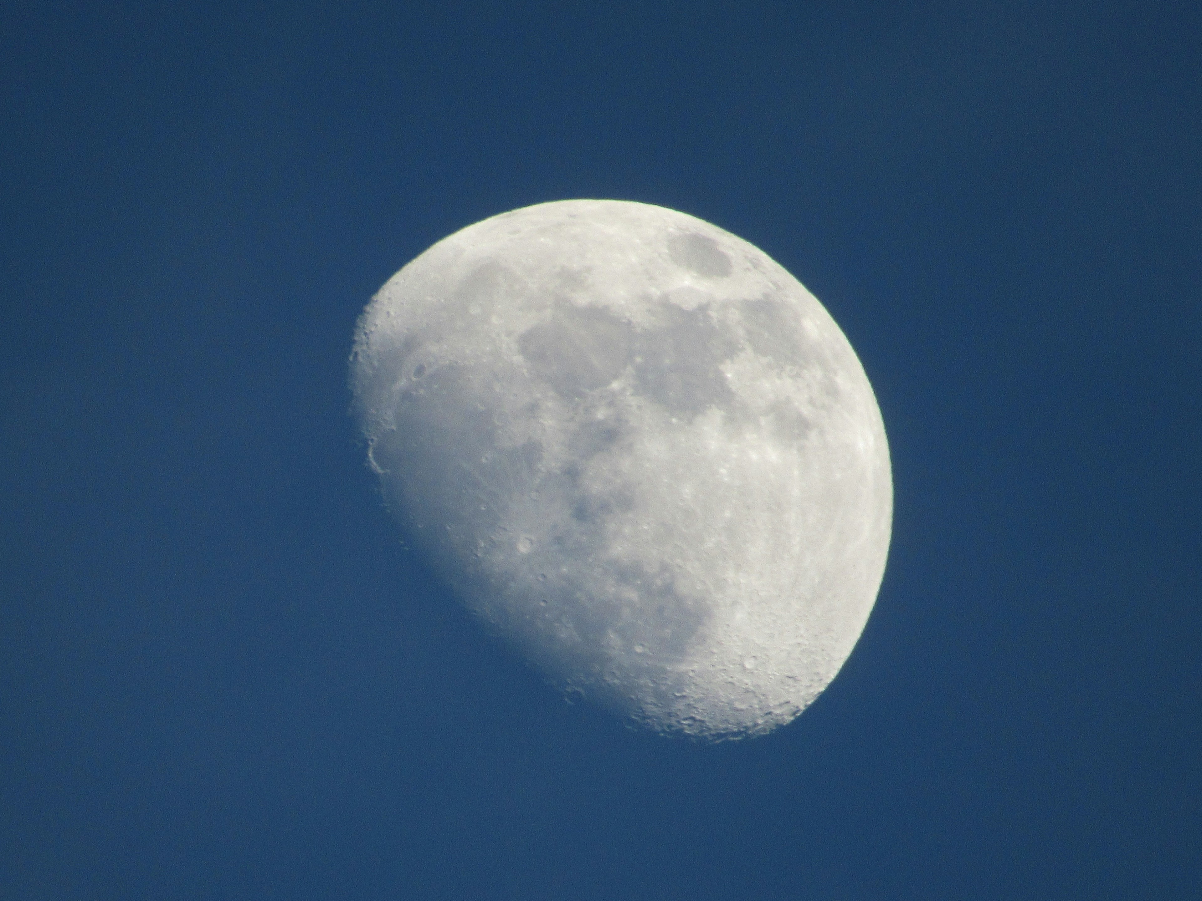 Sichelmond mit sichtbaren Kratern vor blauem Himmel