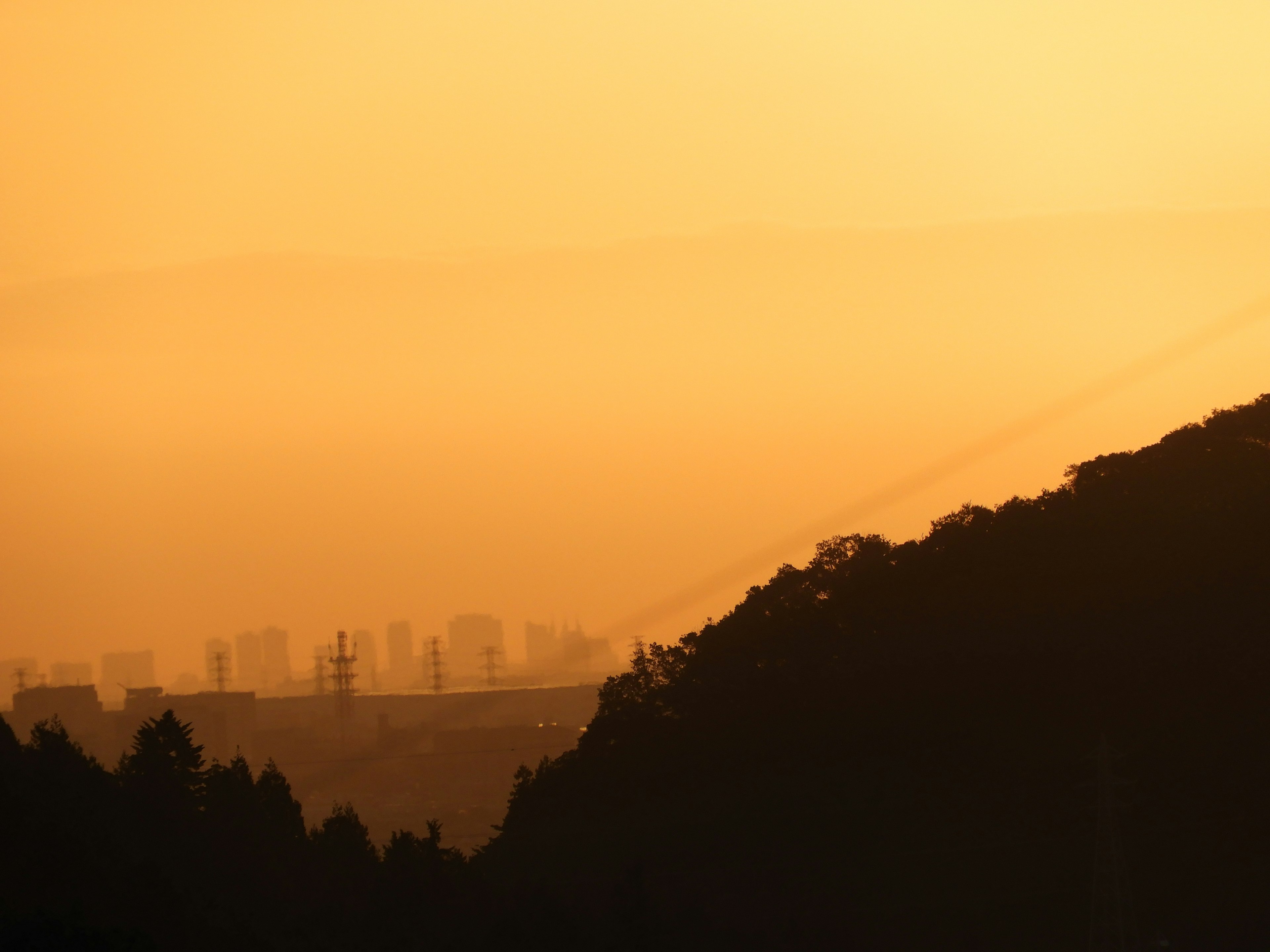 夕焼けのオレンジ色の空と山のシルエットが見える風景