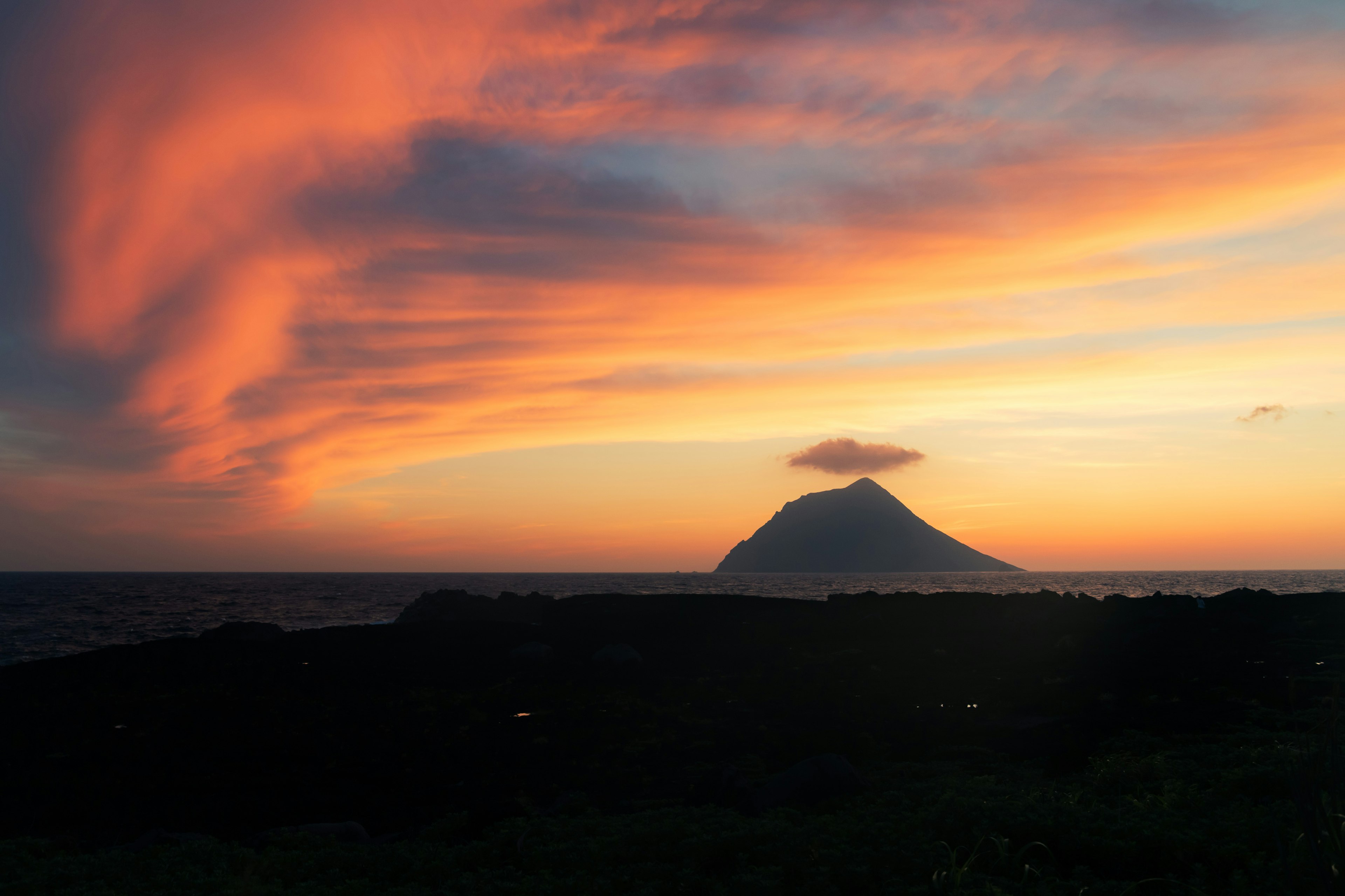 Silhouette de montagne contre un ciel de coucher de soleil coloré au-dessus de l'océan