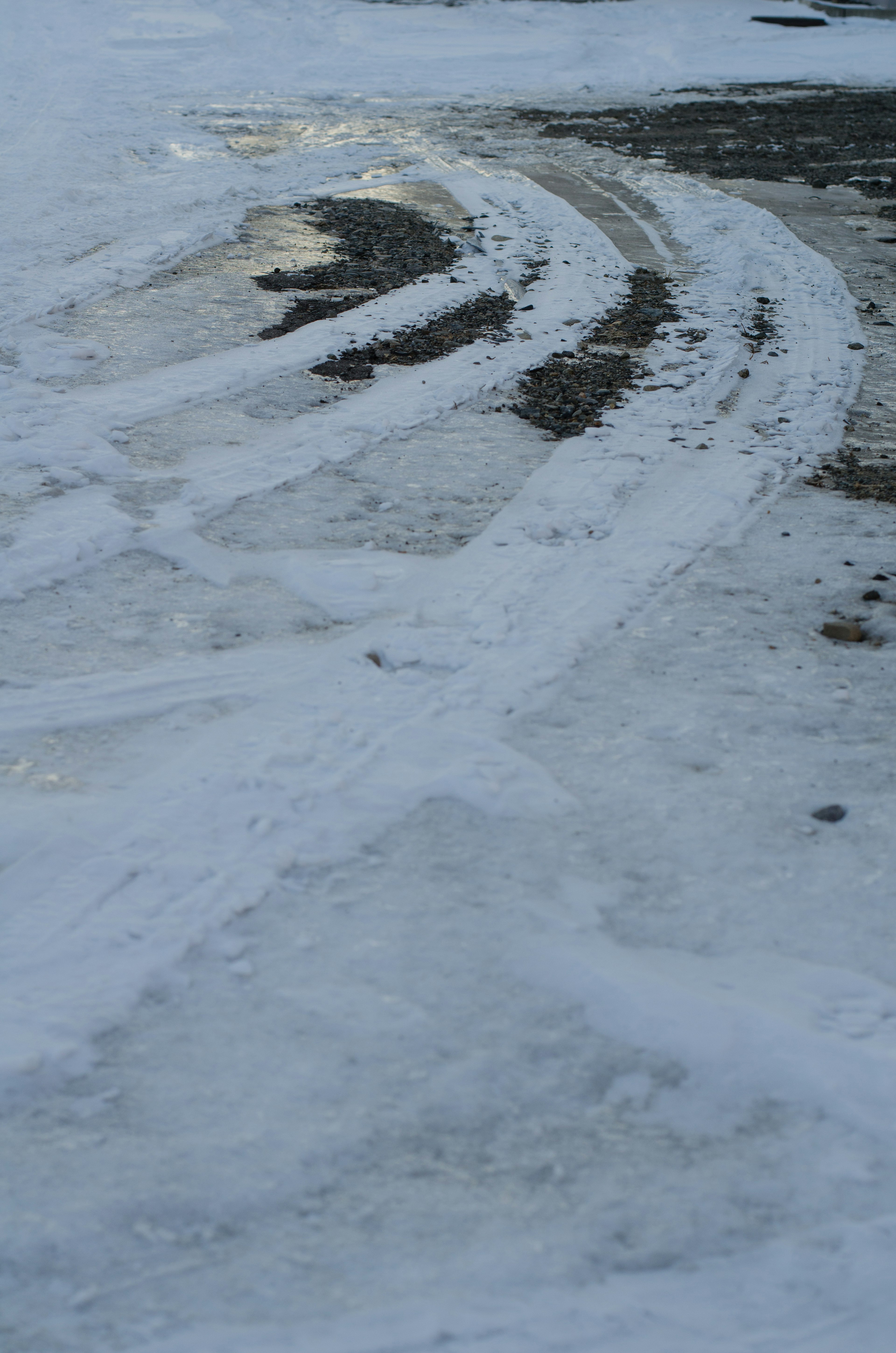 Reifenspuren auf einer schneebedeckten Fläche, die einen gewundenen Weg zeigen